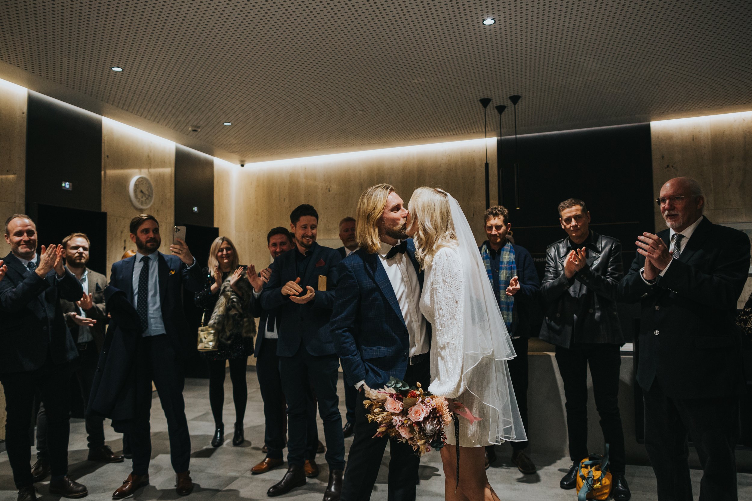 Bride and groom kiss in front of wedding guests.