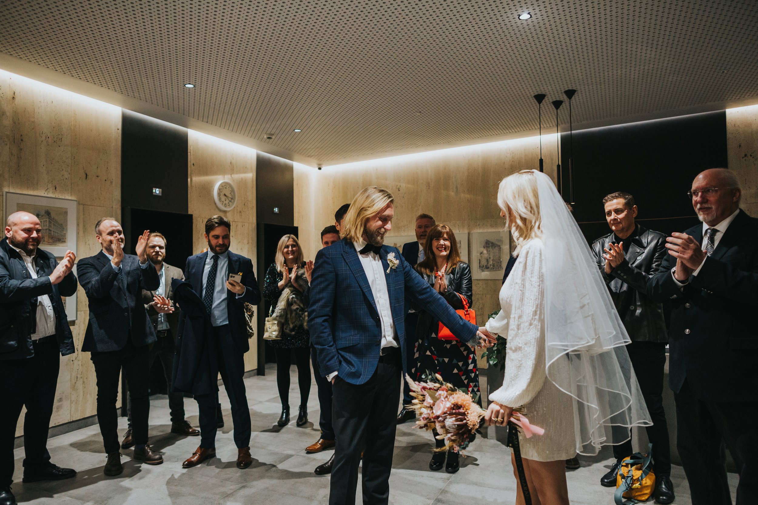 Bride and Groom stand together laughing with their wedding guests in Heron House reception. 