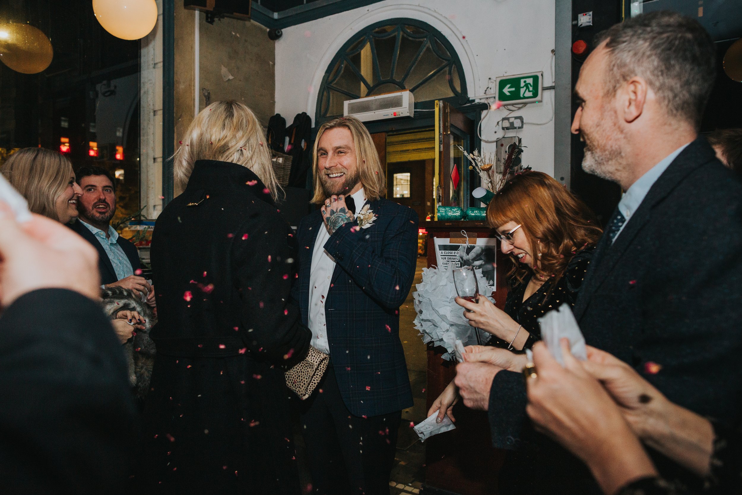 Groom laughs as the confetti flutters over him and his bride. 