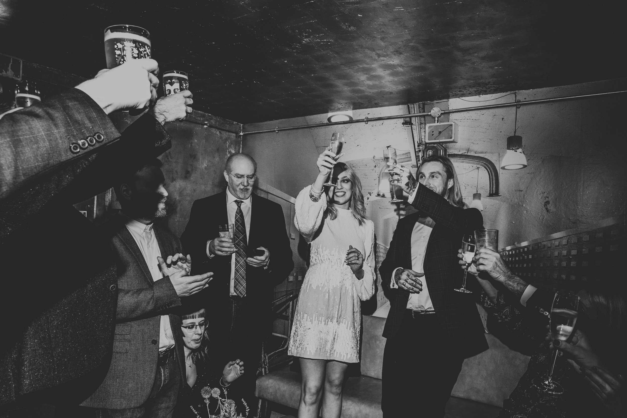 Bride and Groom cheers their guests. Photo in black and white. 