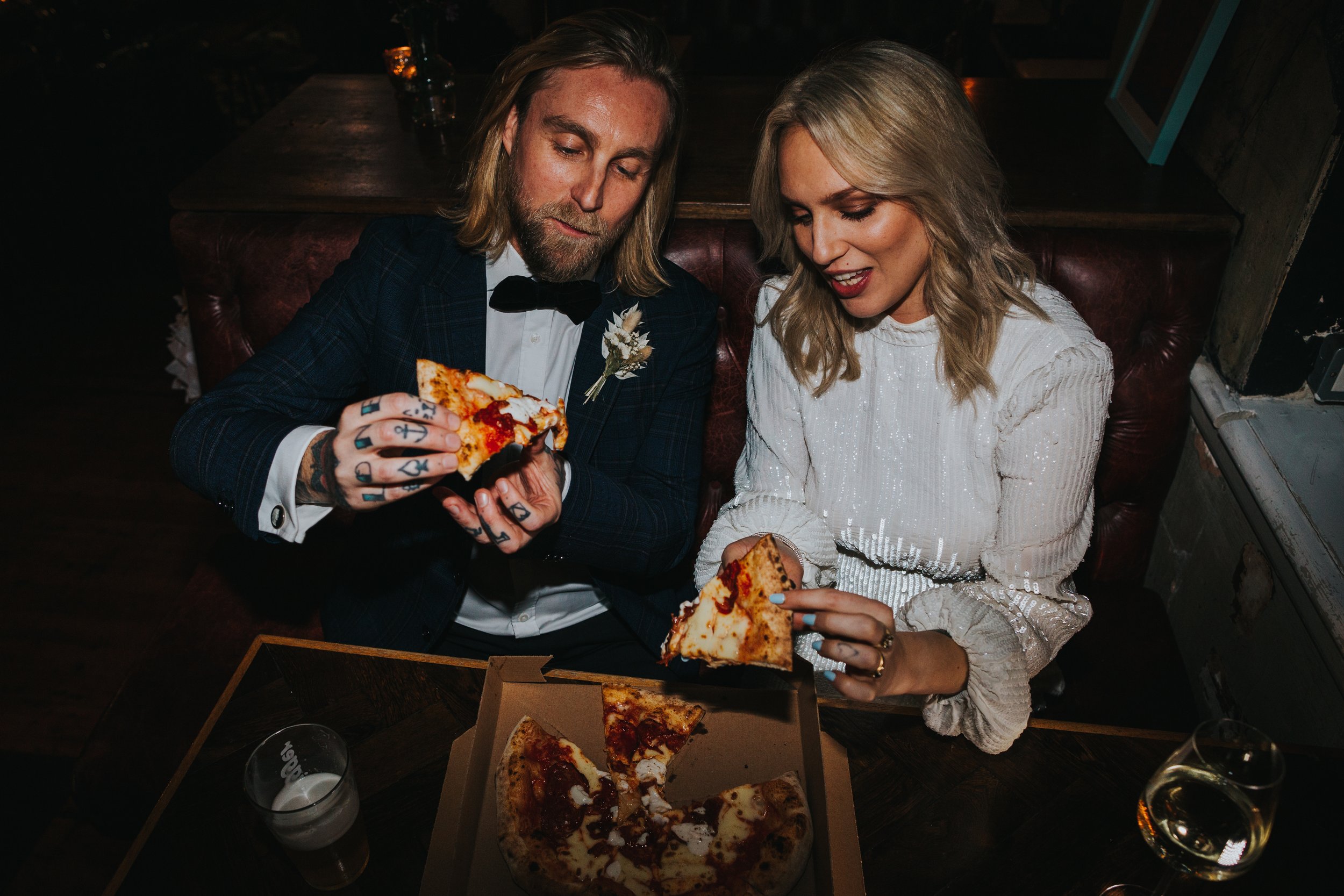 Bride and groom tuck into a boxed pizza on their wedding day. 