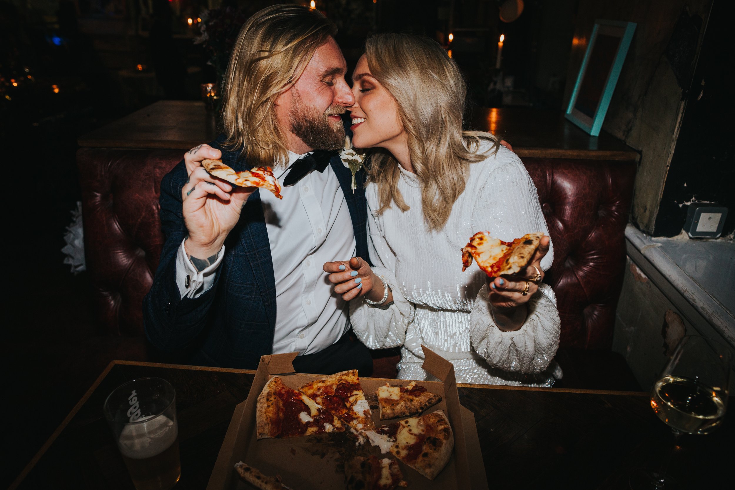 Couple kissing at they hold pizza. 