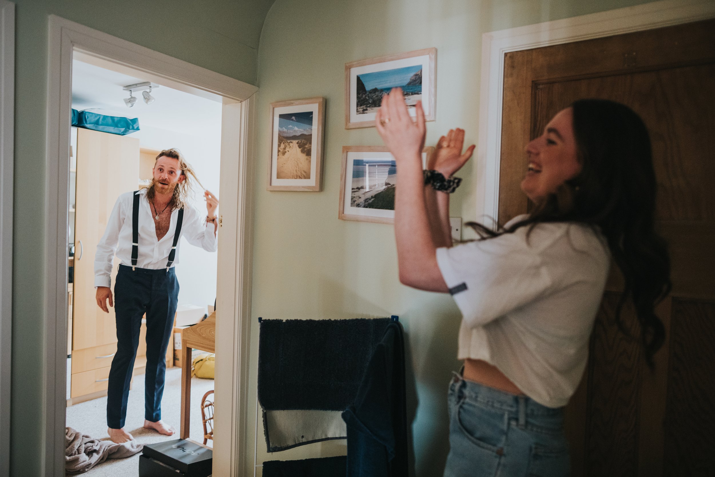 Bridesmaids claps as her friend poses with wet hair in doorway. 