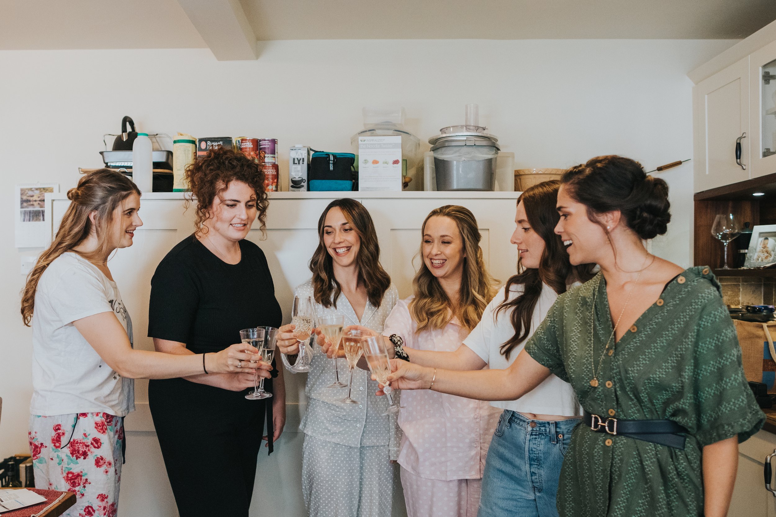 Bride has a glass of Champagne with her bridesmaids. 