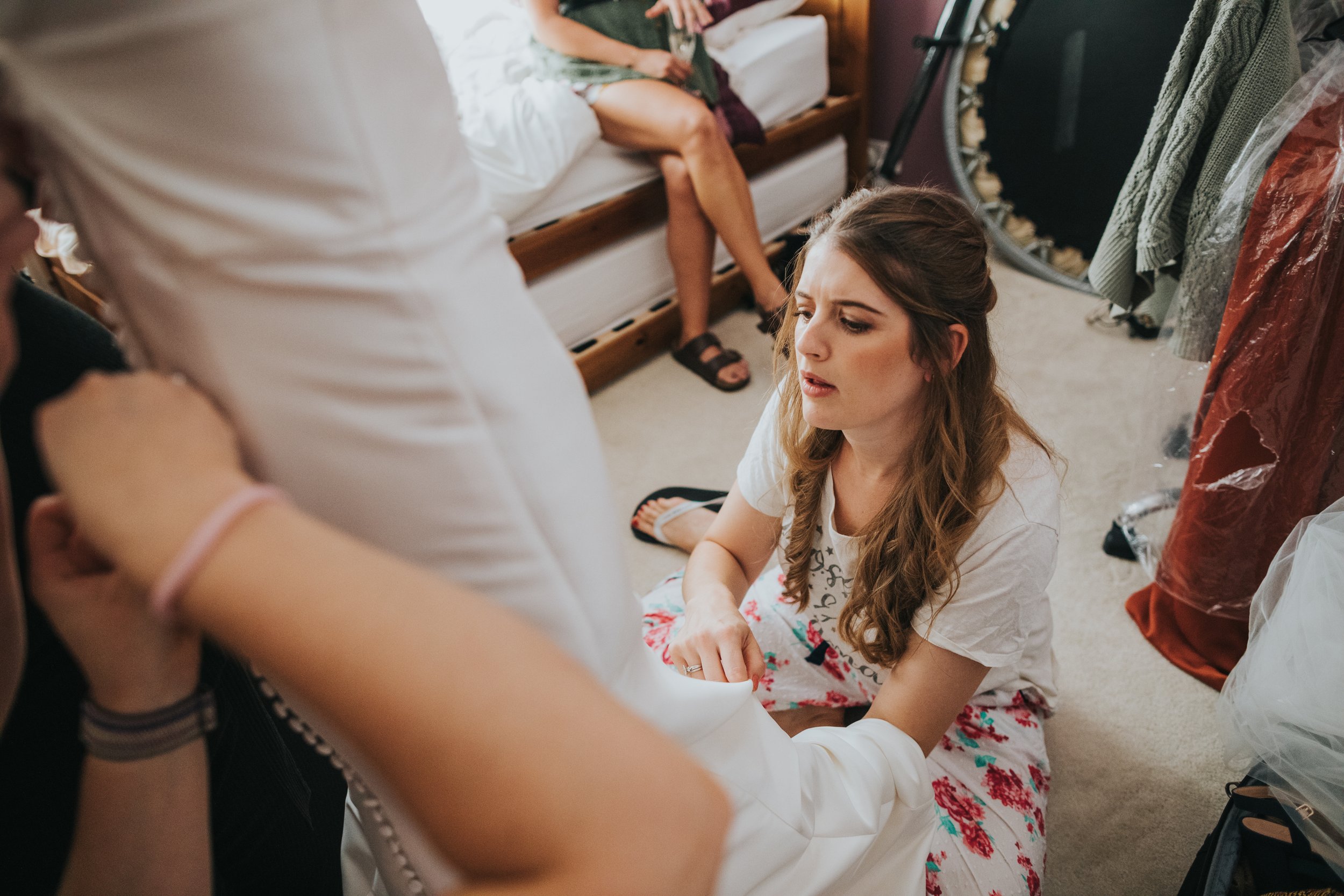 Bridesmaid helping bride with her dress. 