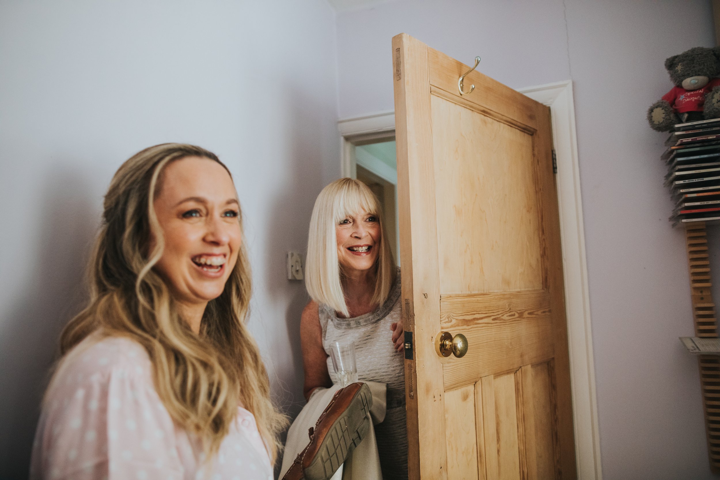 Brides mother pops her head in the door to see her daughter wearing her wedding dress.