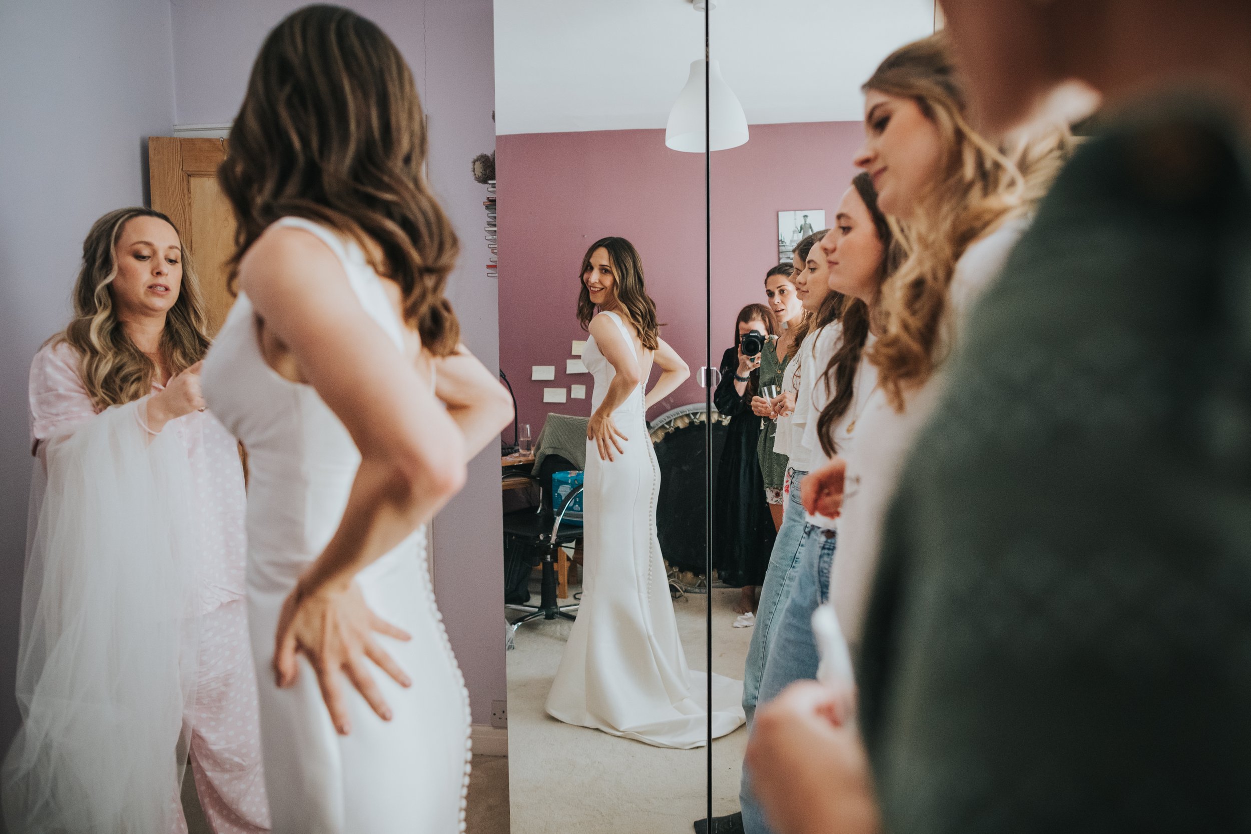 Bride looks at her full length reflection in the mirror. 