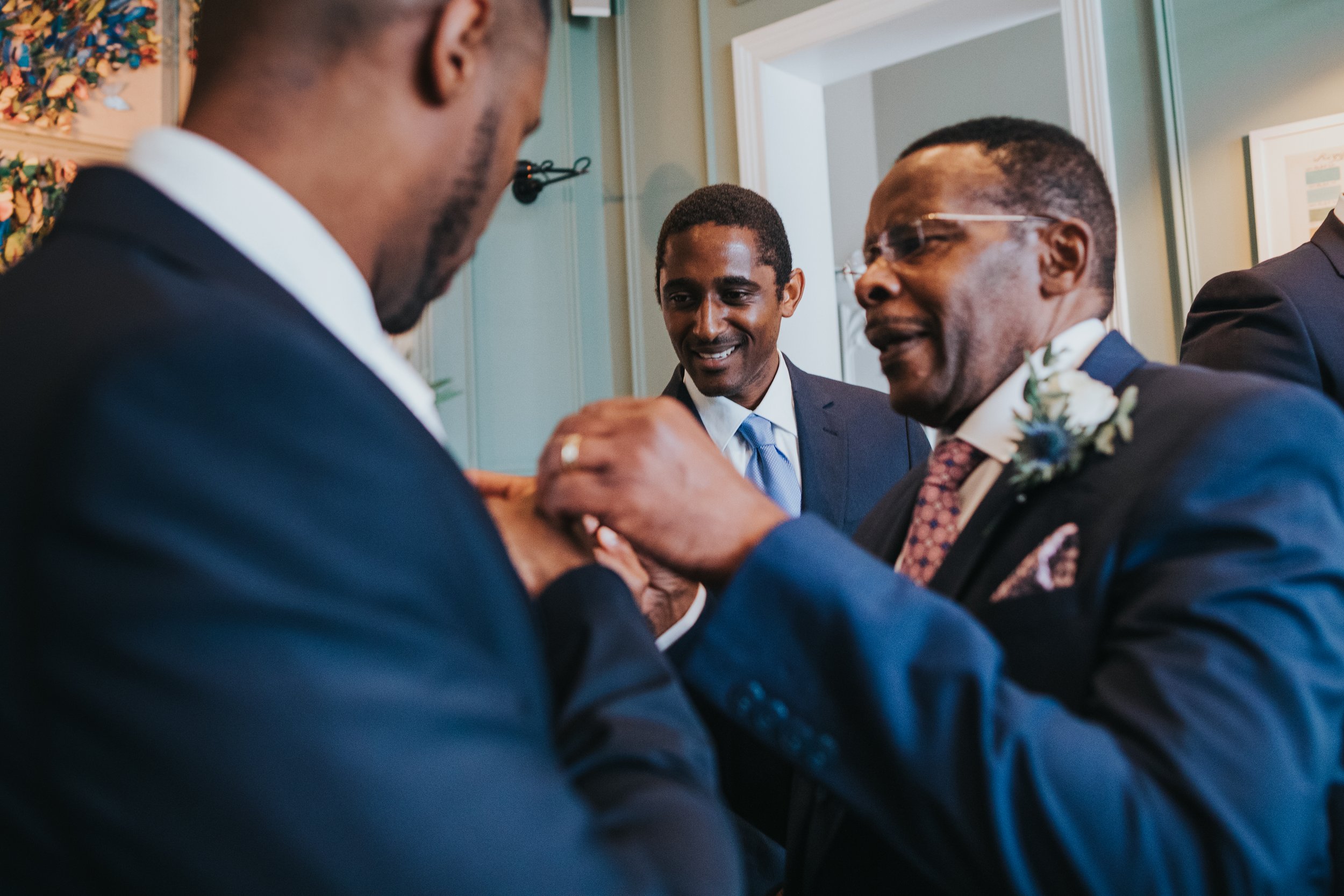 Grooms Father puts button hole on on groom on his wedding day.