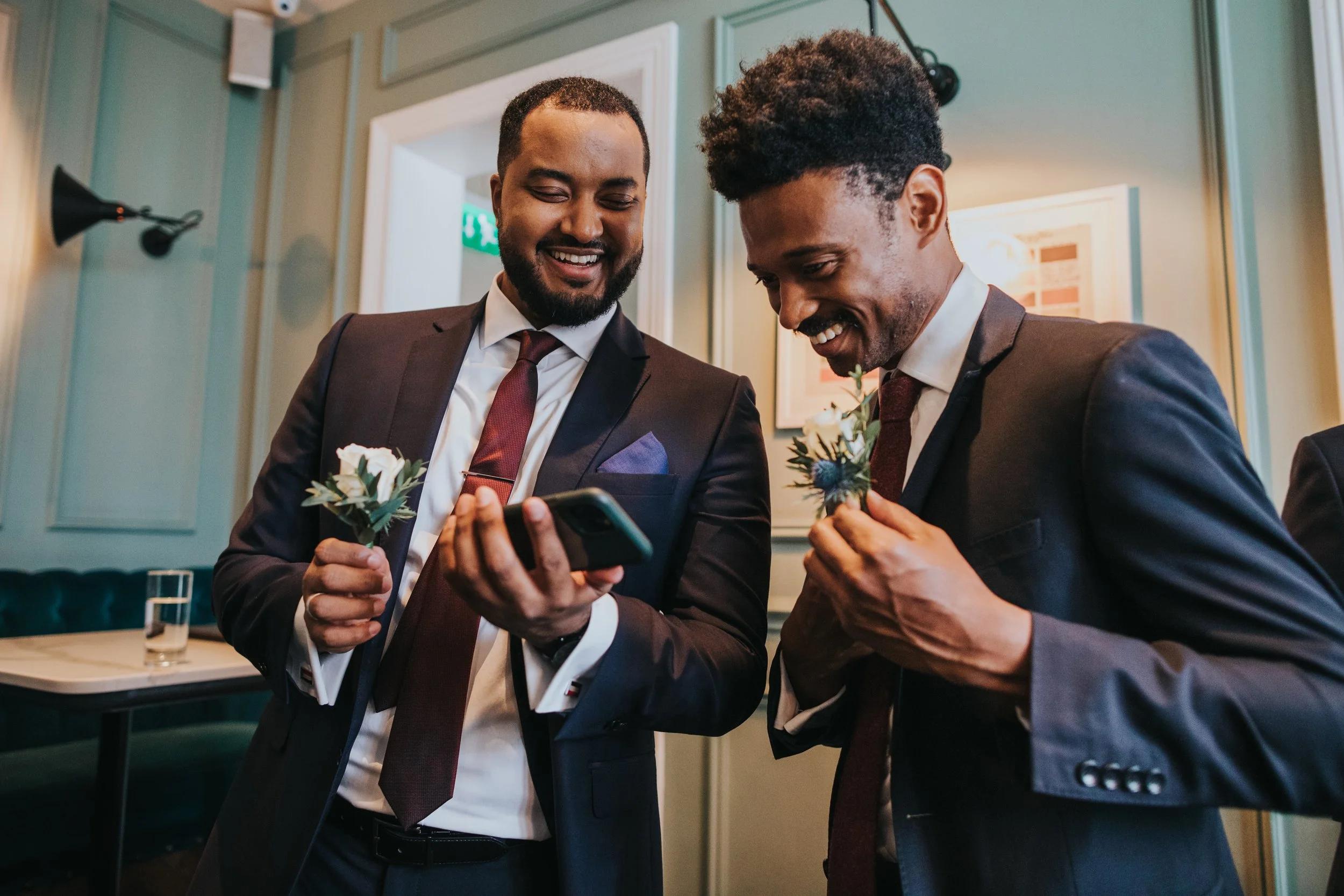Groomsmen laughing at something on iPhone. 