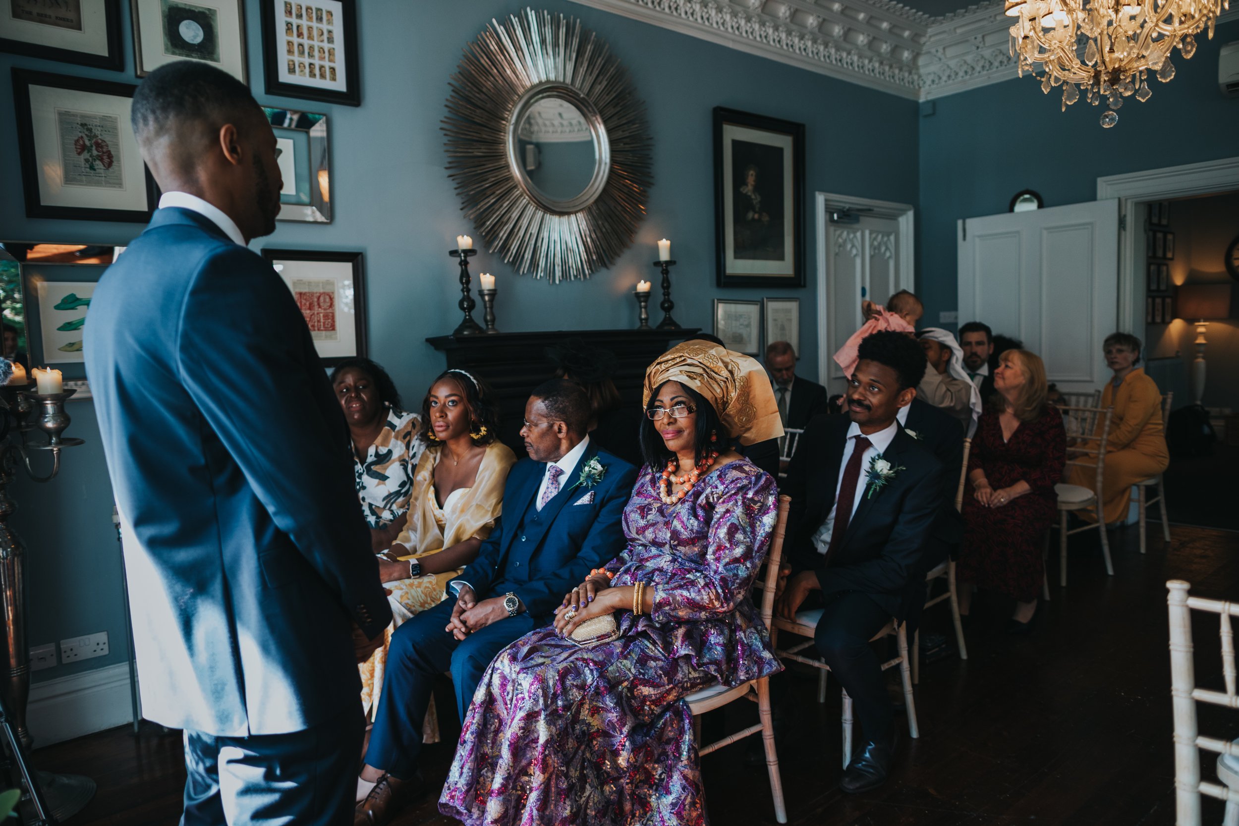 Grooms mother wearing amazing colourful dress and head dress gives her son a meaningful look.  