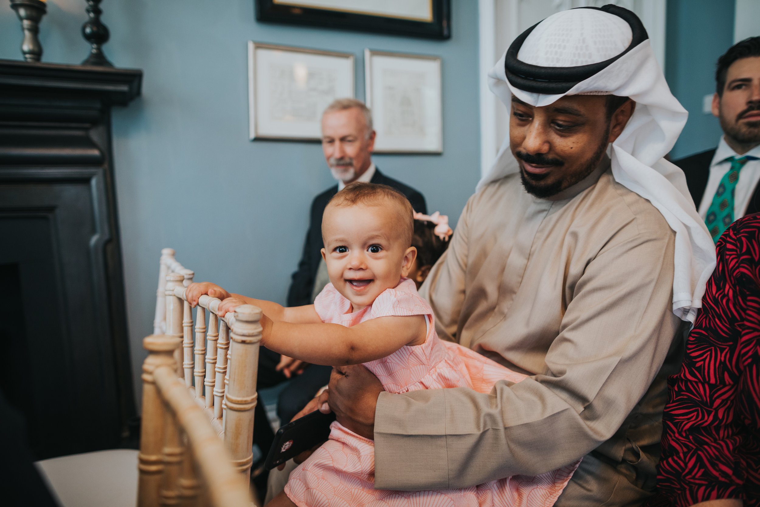 Man wearing keffiyeh holds smiling baby. 