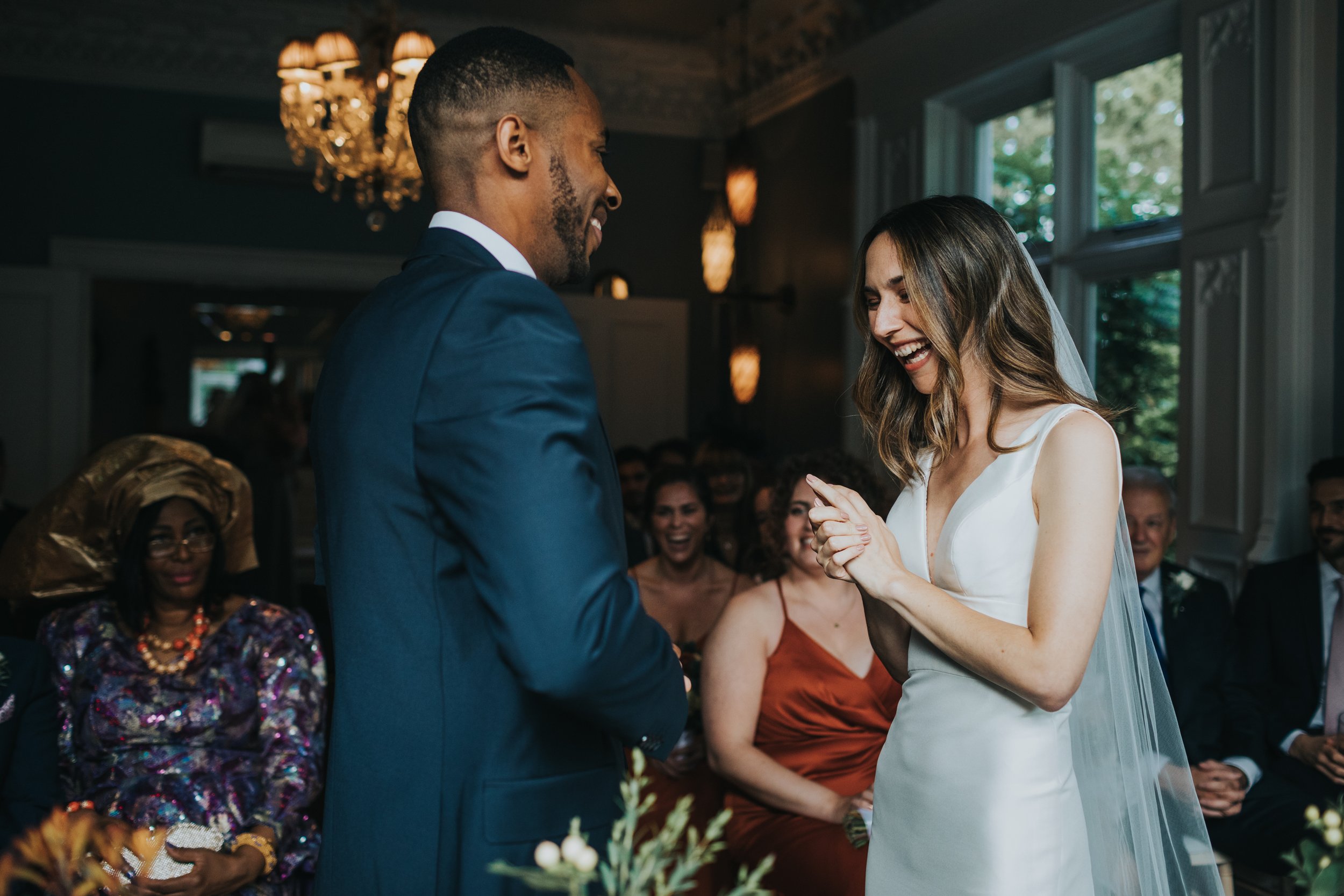 Bride laughing and holding her wedding ring. 