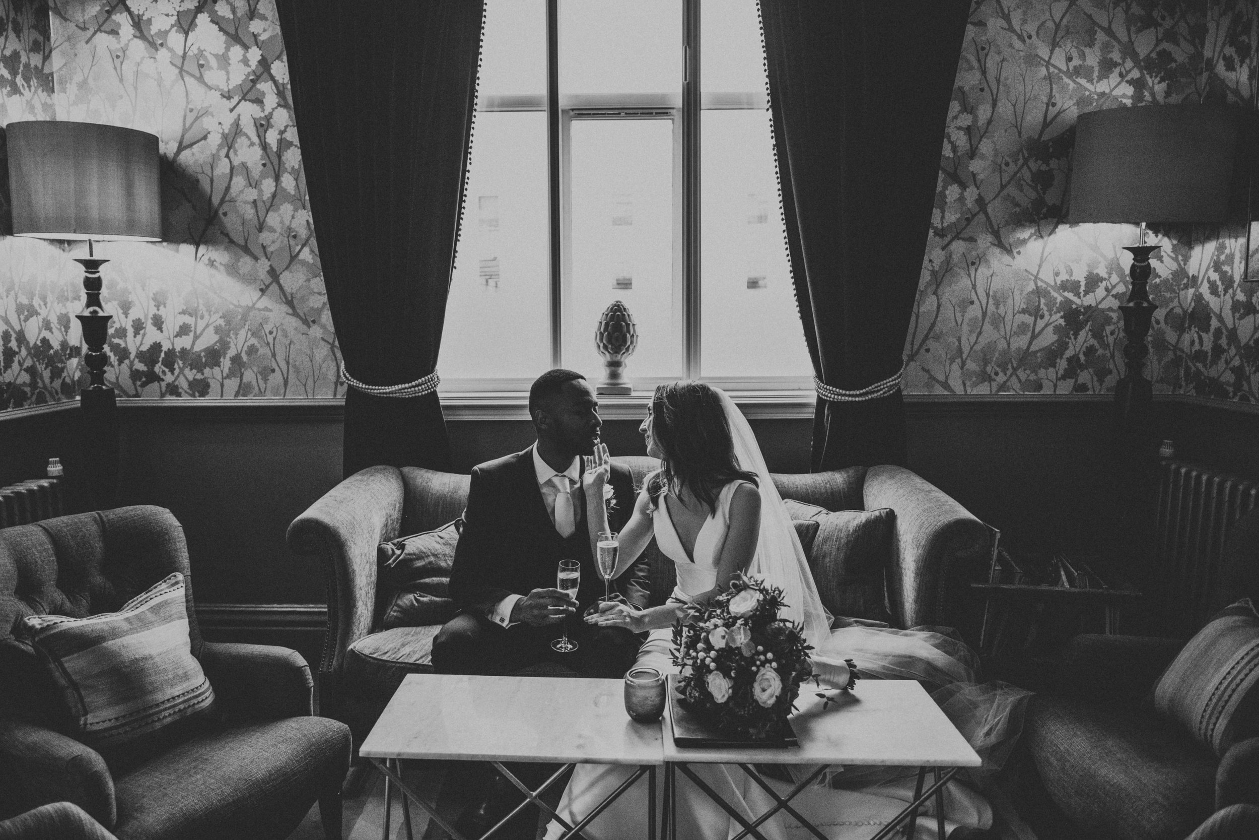 Black and white photo of Bride and Groom sitting on the sofa together at Didsbury House. 