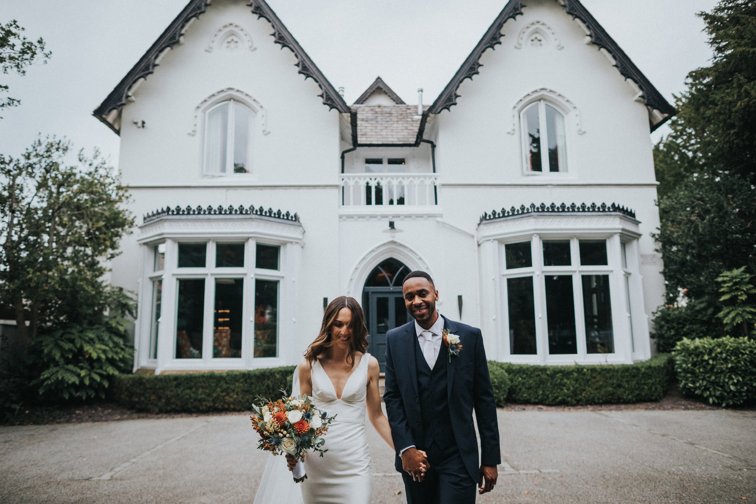 Bride and Groom walking in front of Didsbury House Hotel.