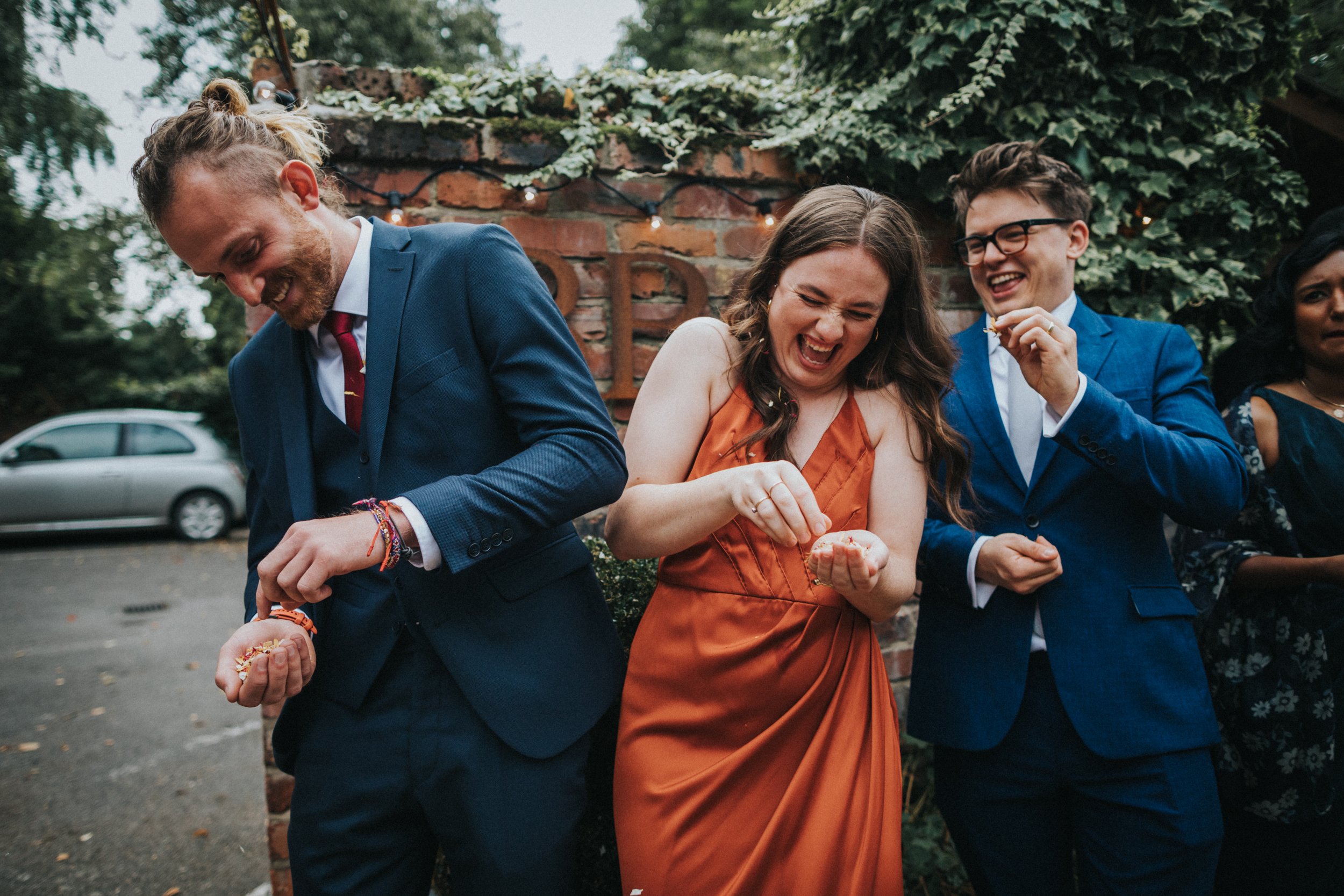 Wedding guests laughing holding confetti. 