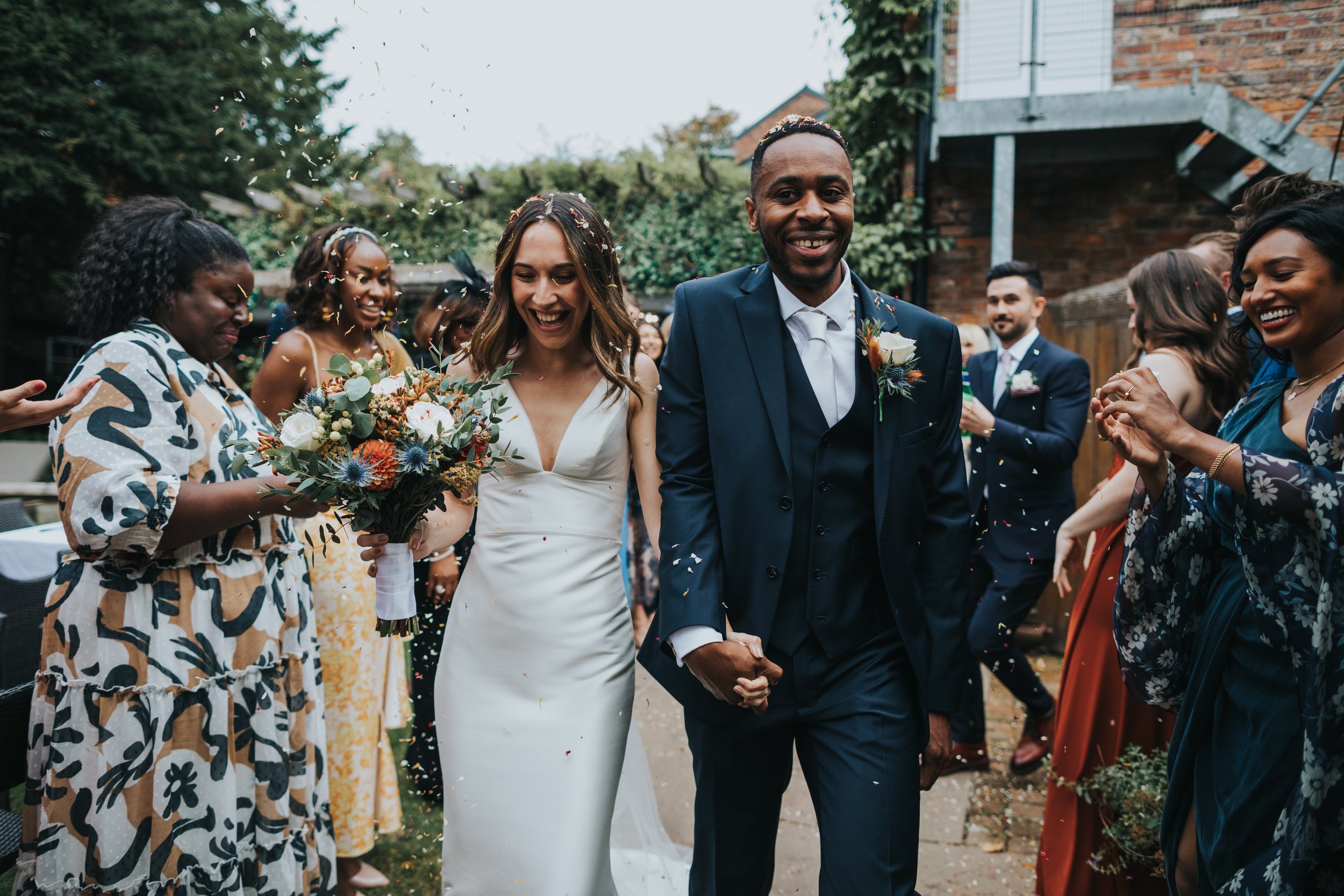 Bride and groom smiling together with confetti in the air around them. 