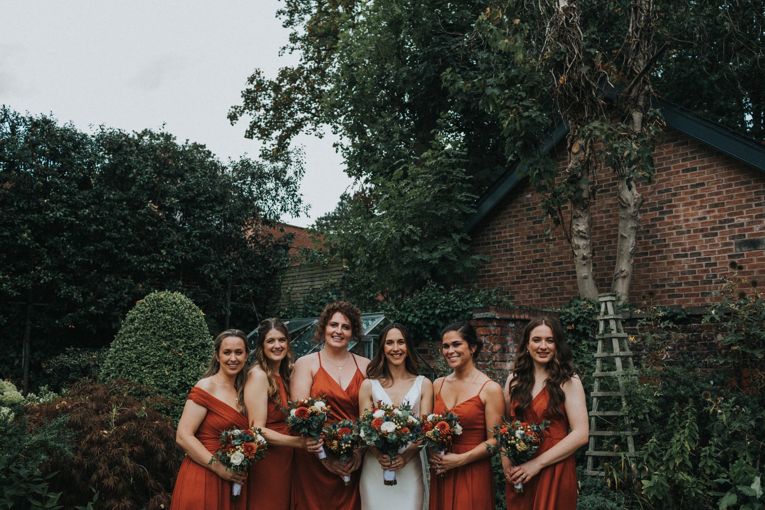 Bridesmaids have photo together in front of greenhouse.