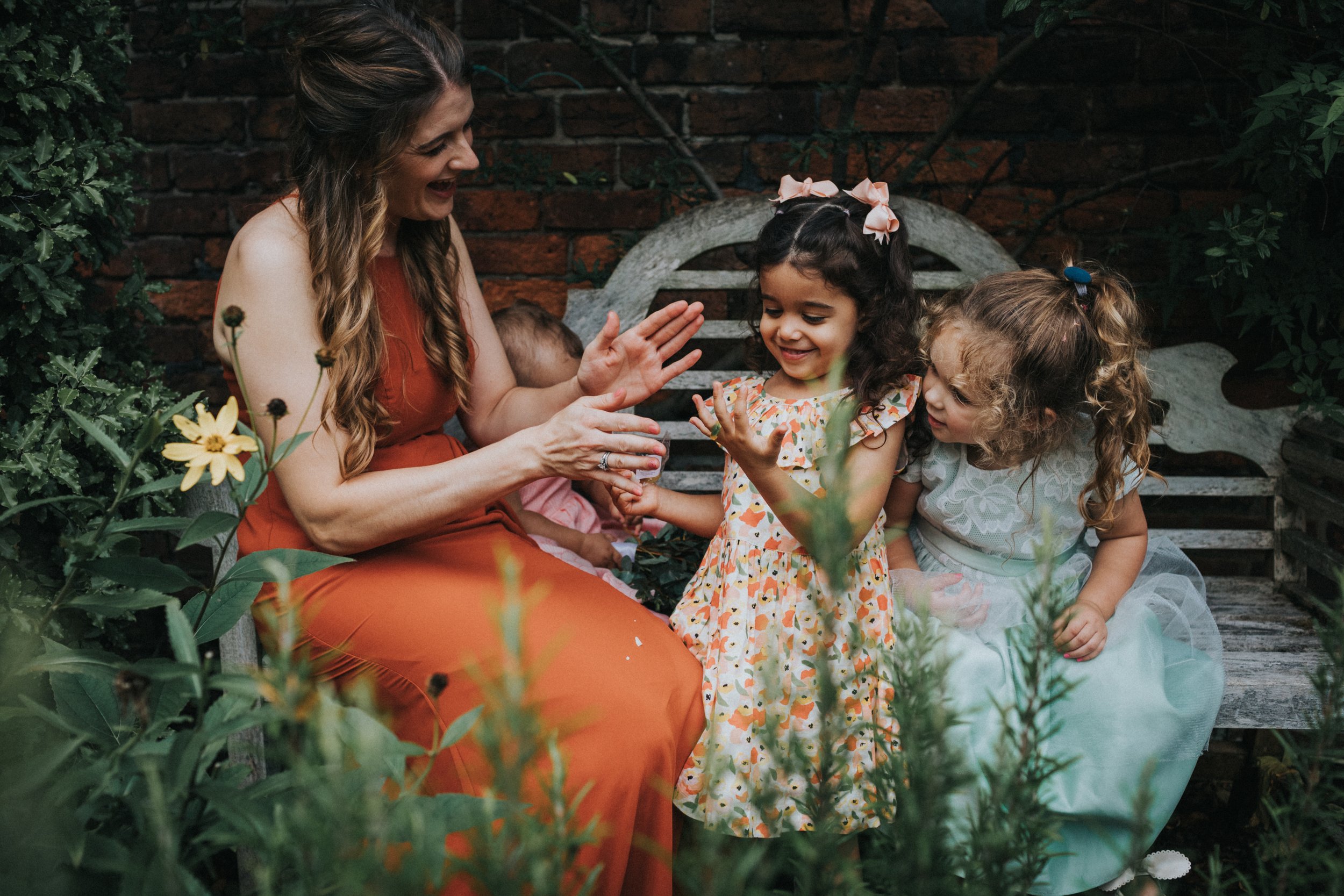 Bridesmaid playing with children on garden bench.