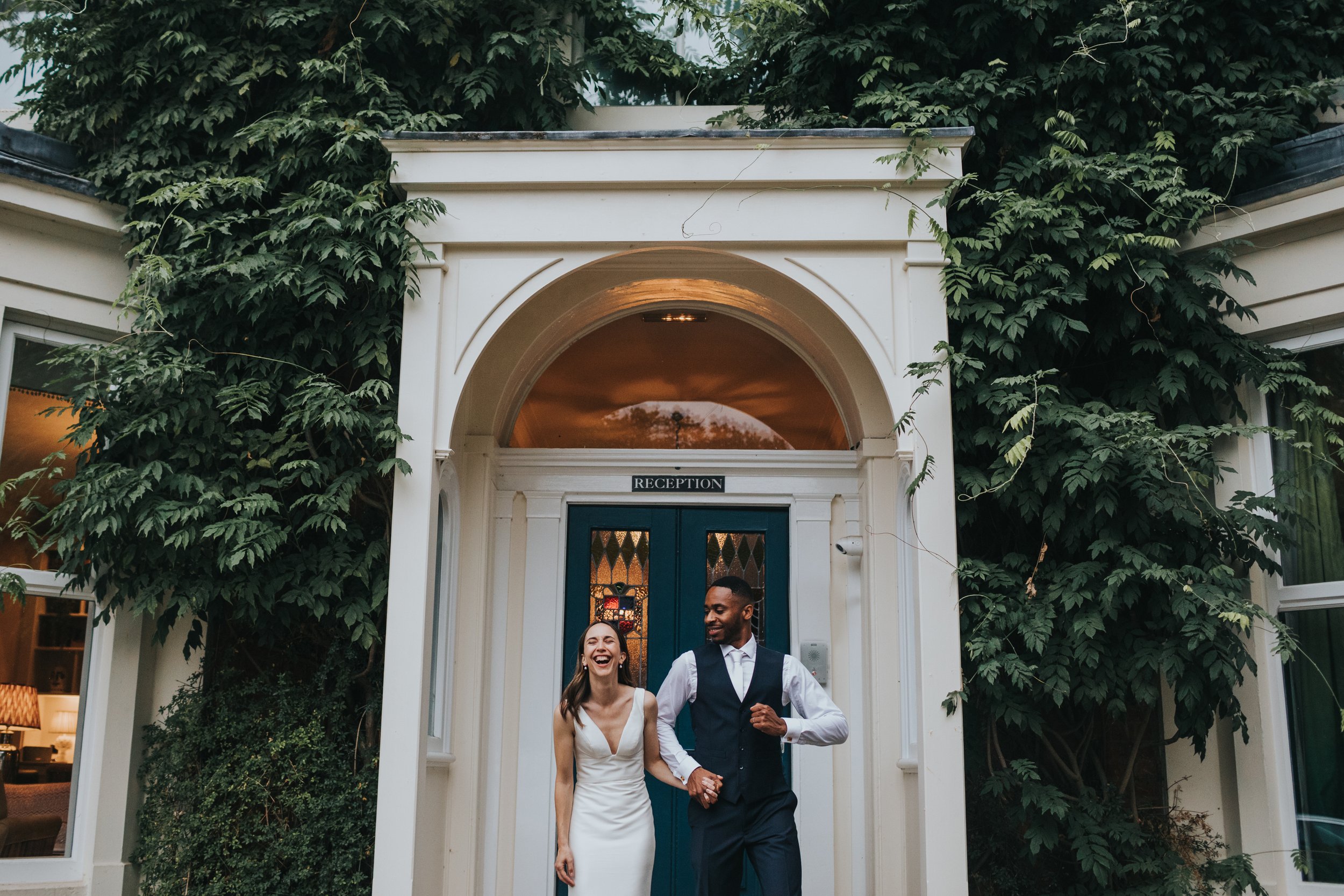 Bride and groom have a photo in the doorway of Eleven Didsbury Park