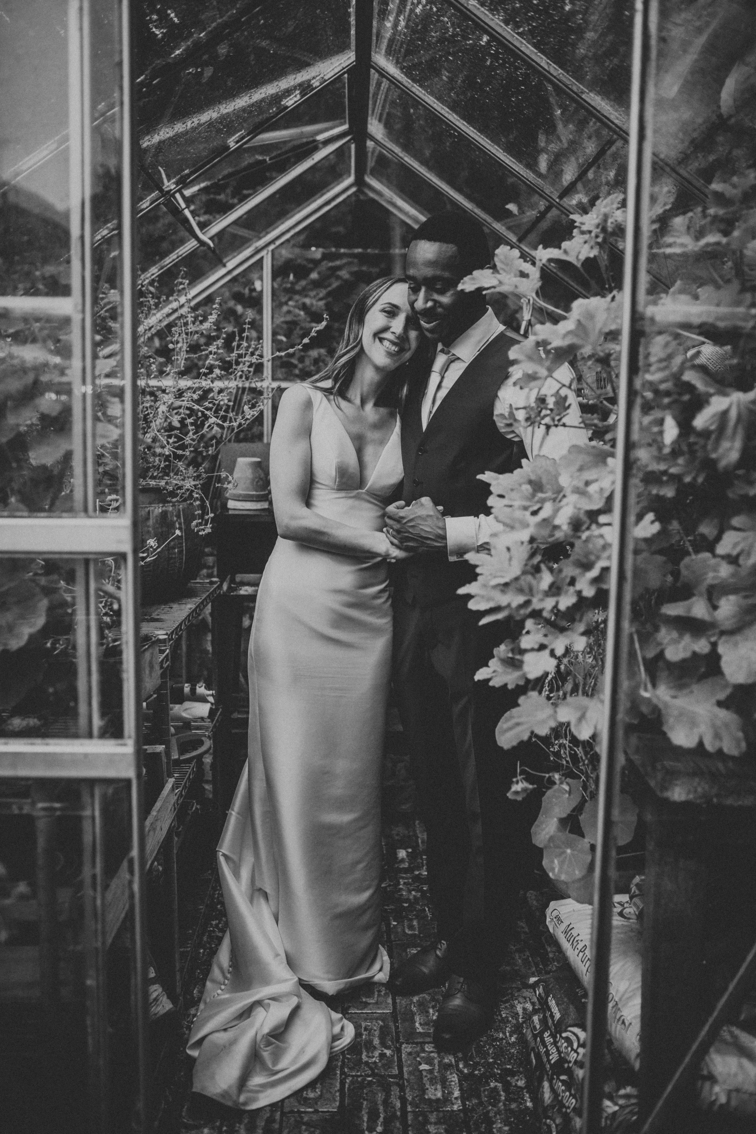 Black and white photo on bride and groom in greenhouse. 
