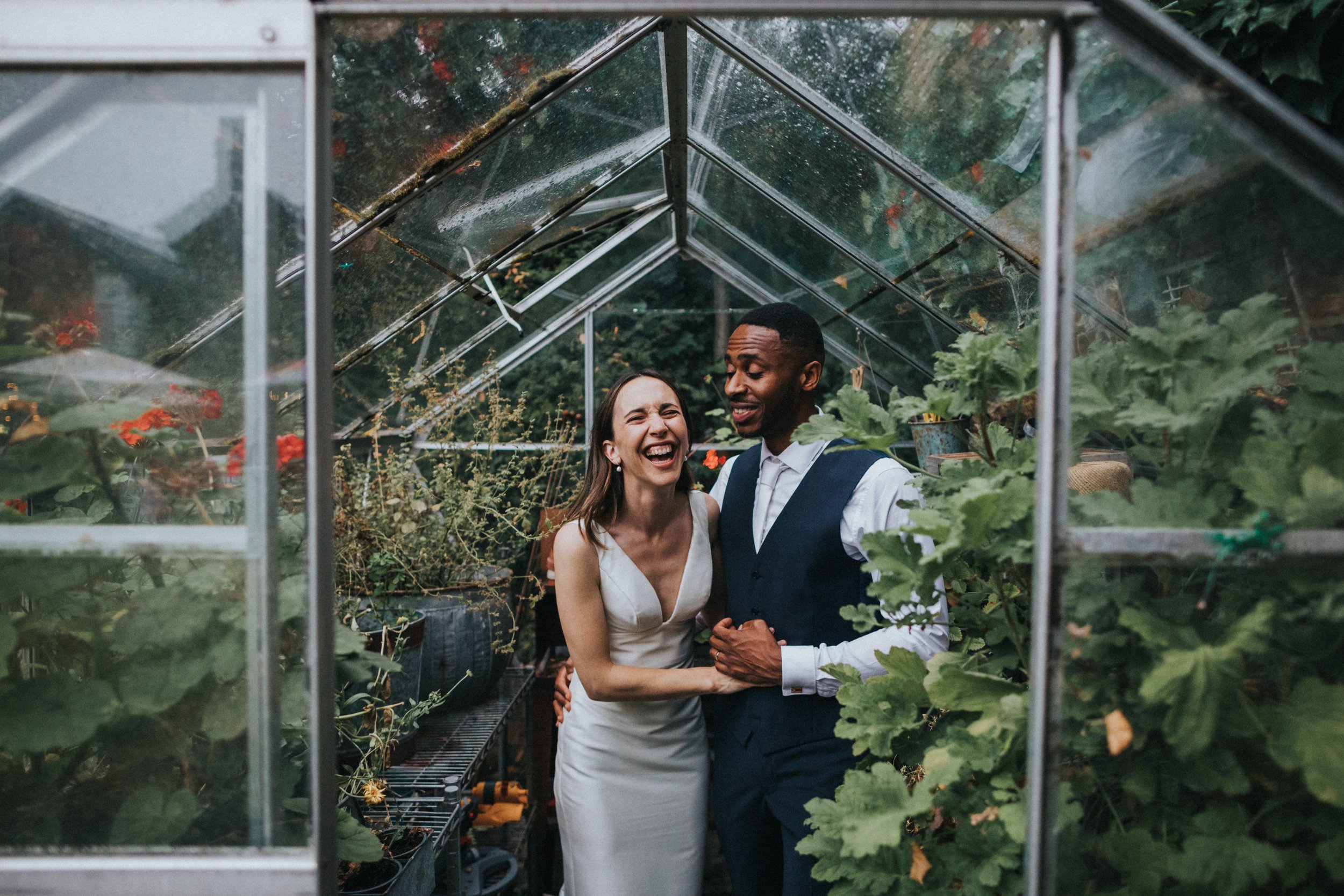 Colourful photo of Bride and Groom in greenhouse full of plants. 