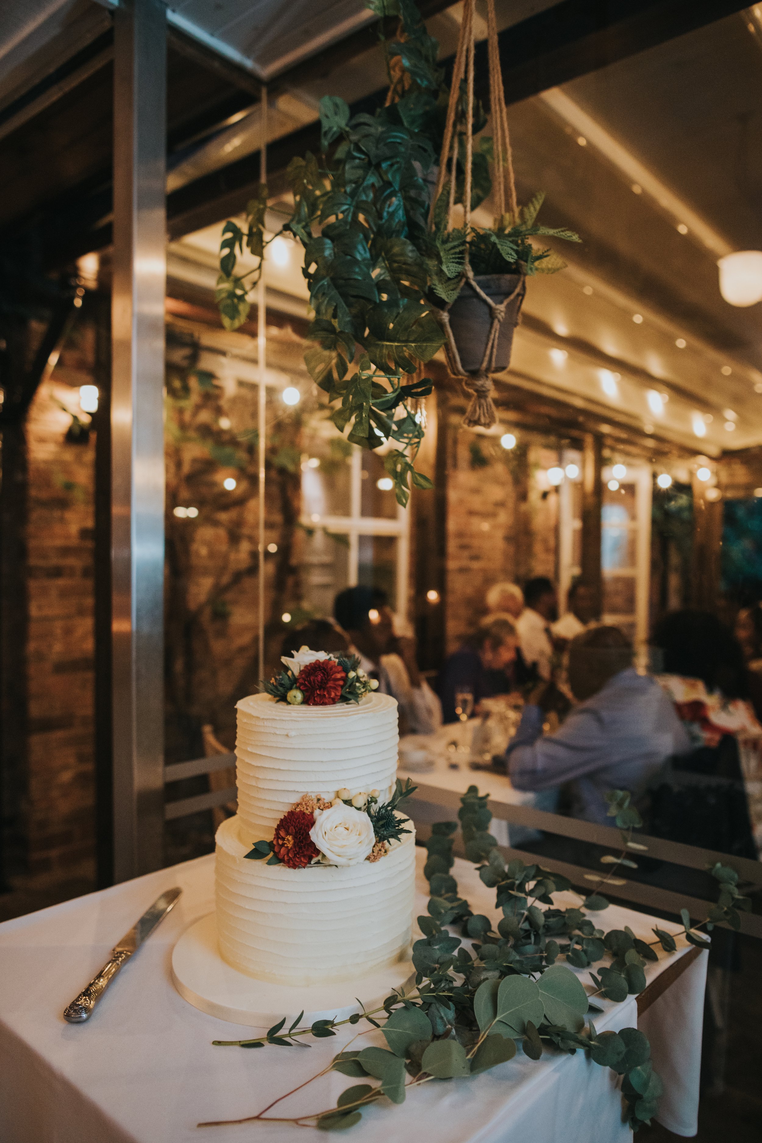 Wedding cake with plants dangling above it. 