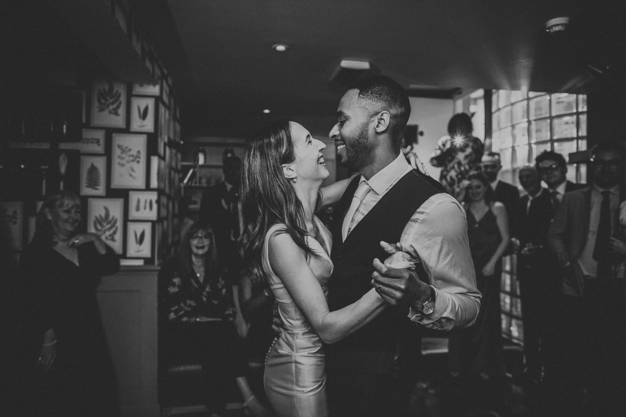 Bride and groom laughing during first dance, photo in black and white. 