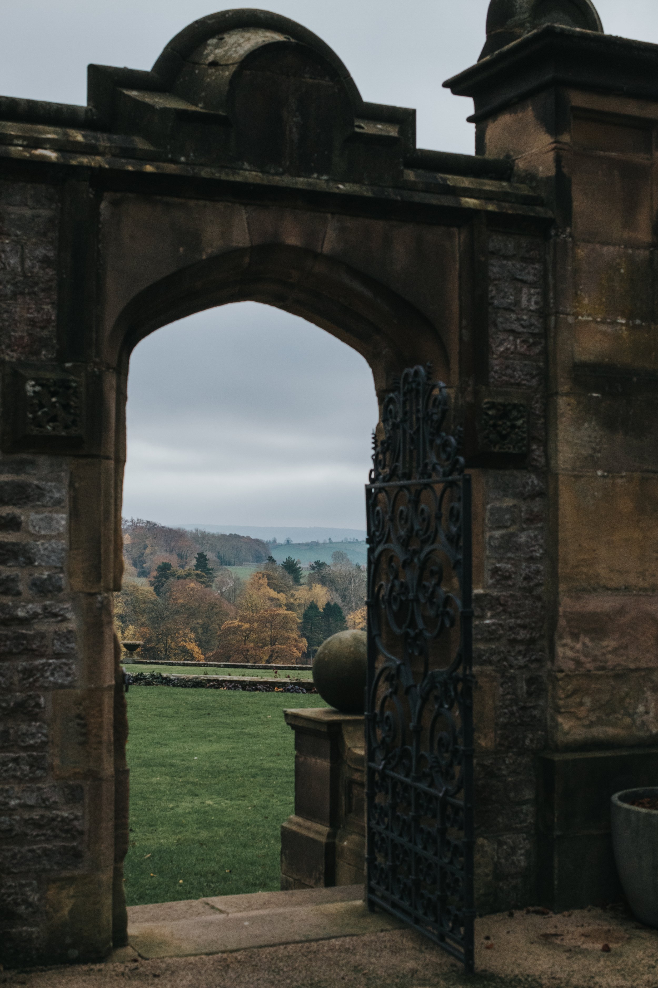 Archway leading onto the back garden of Thornbridge Hall, autumnal trees in the distance.