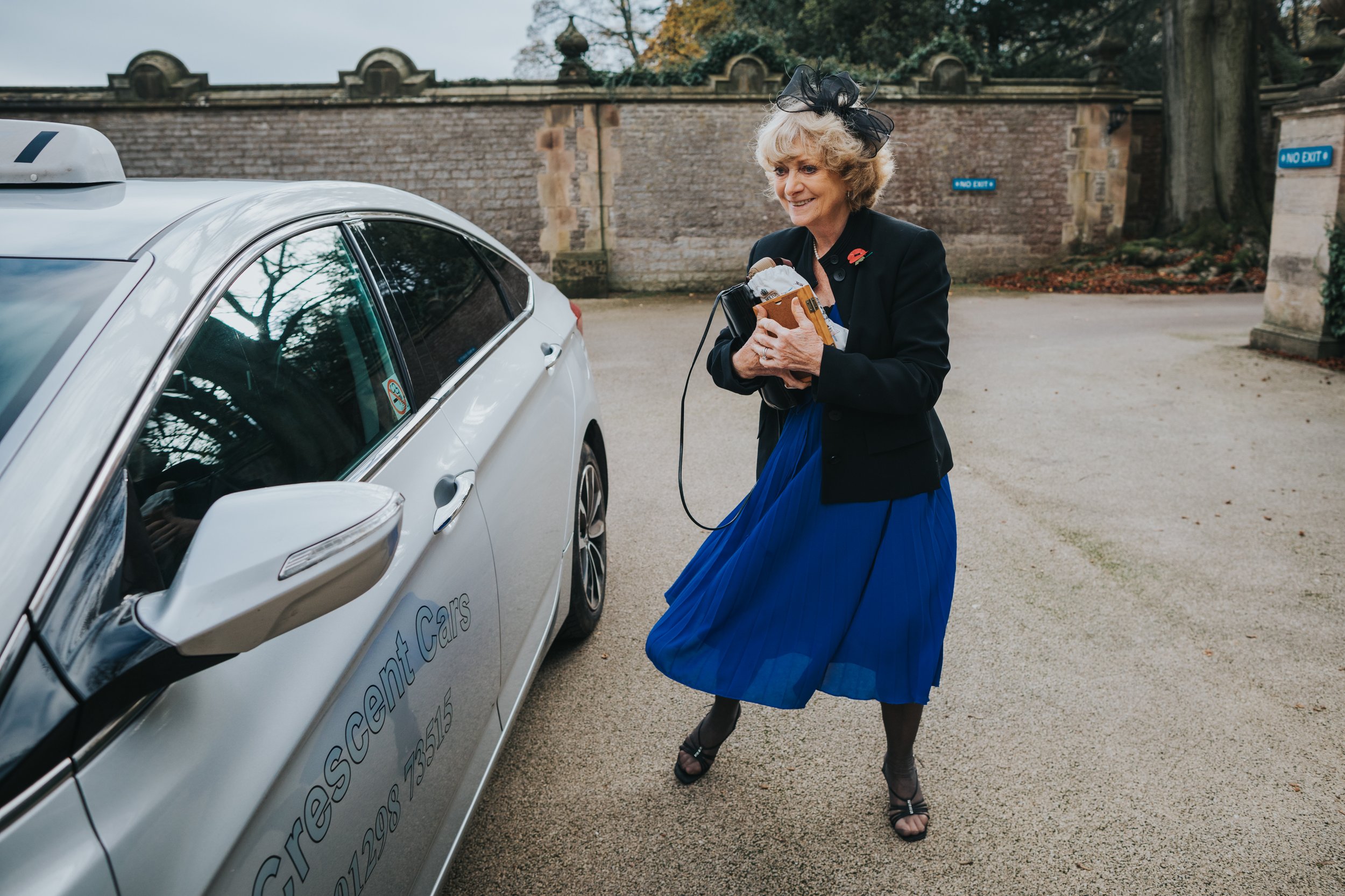 Wedding guest arrive by taxi wearing a navy blue dress.