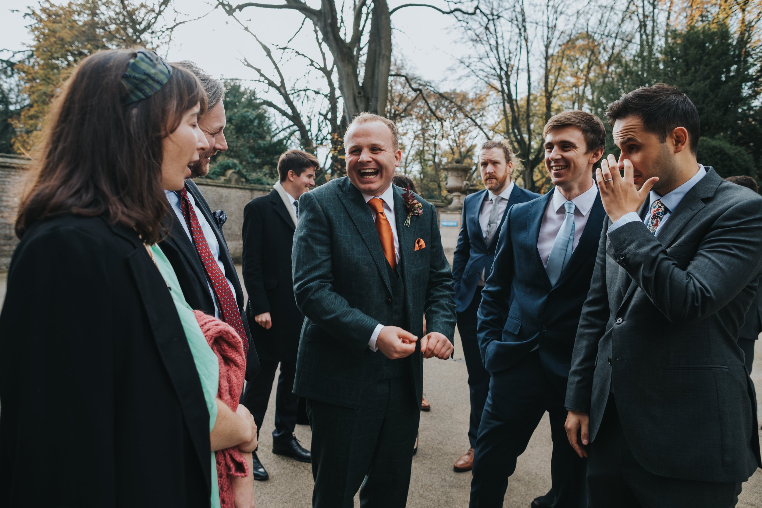 The groom laughs as he greets wedding guests outside Thornbridge Hall. 