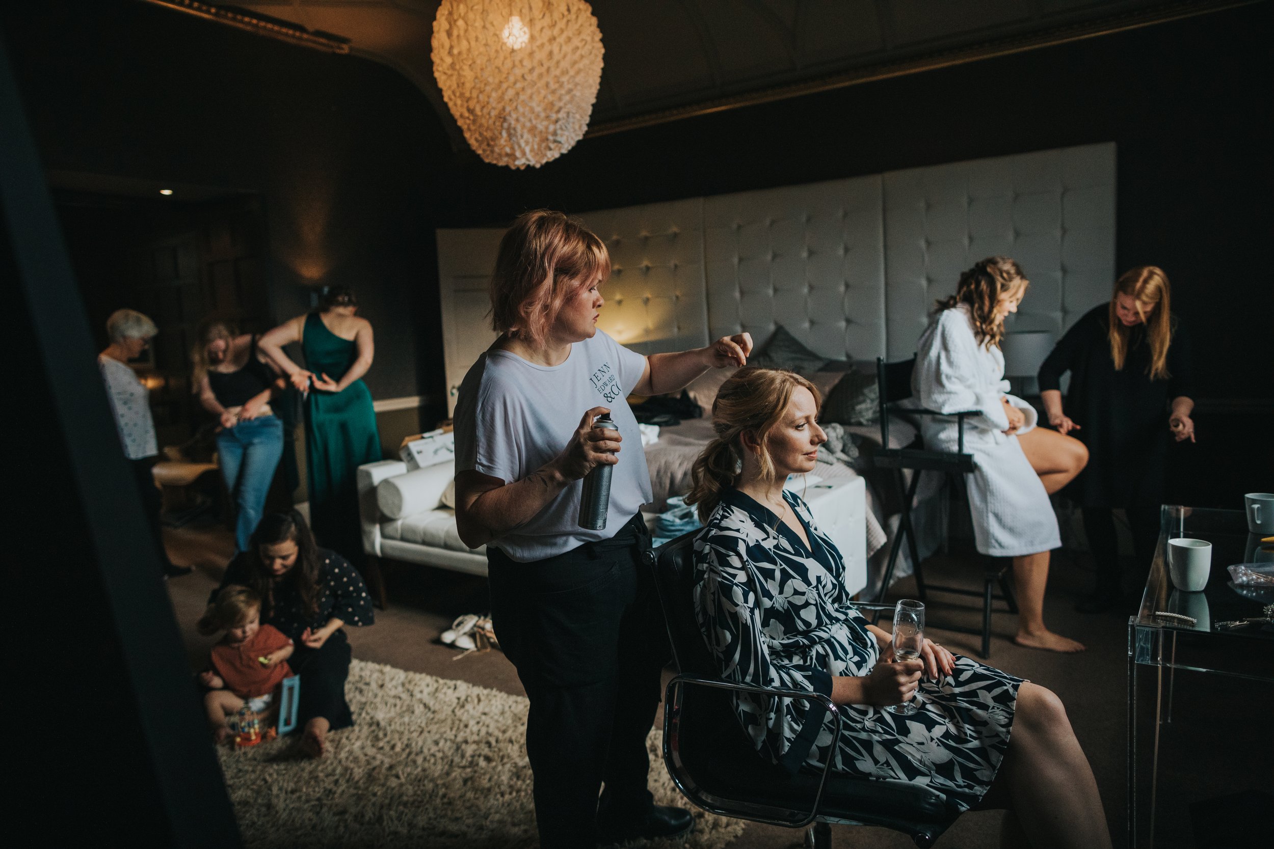 Bride has her hair done while bridesmaids get ready around her. 