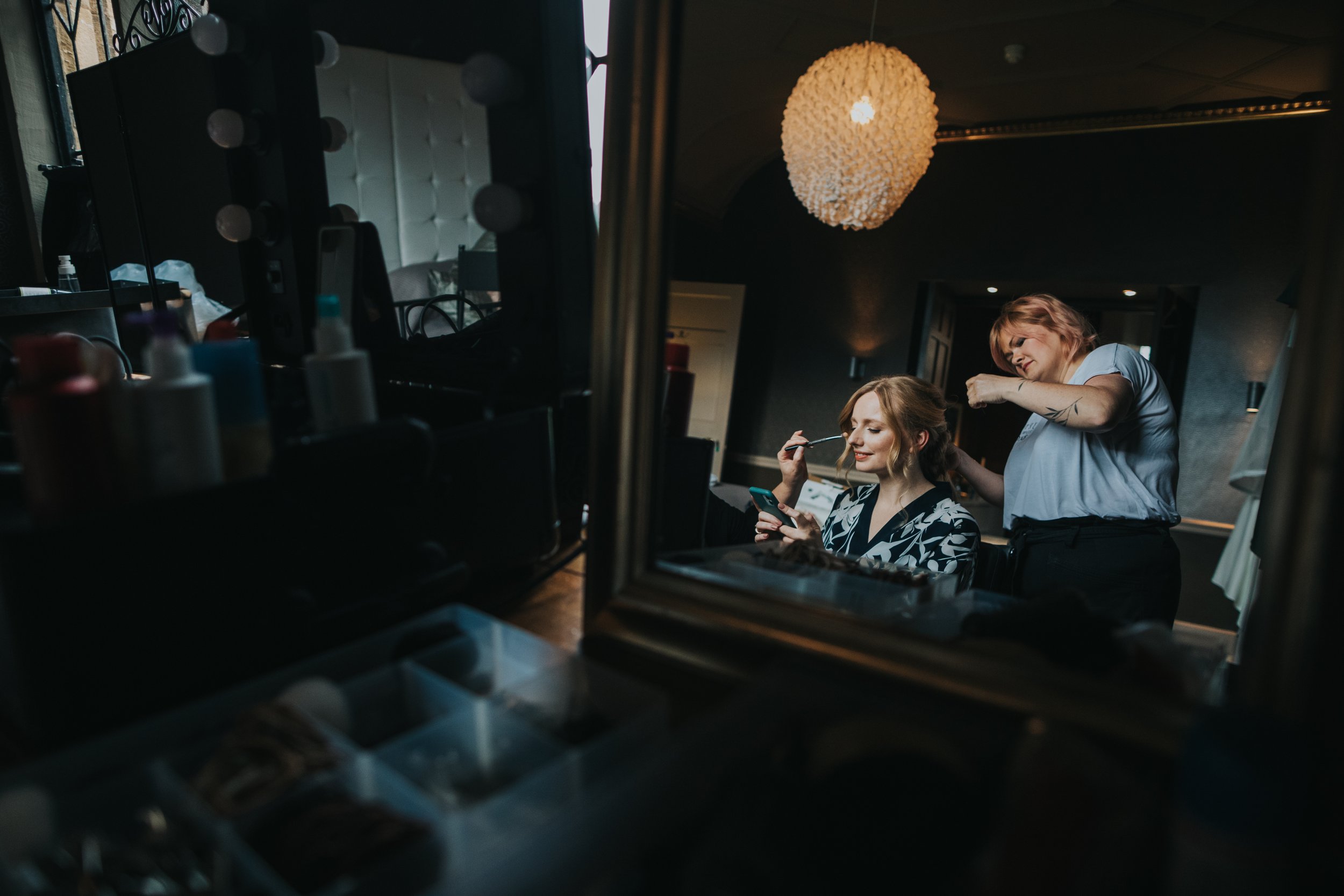 Reflection of bride getting her make up done in the mirror. 