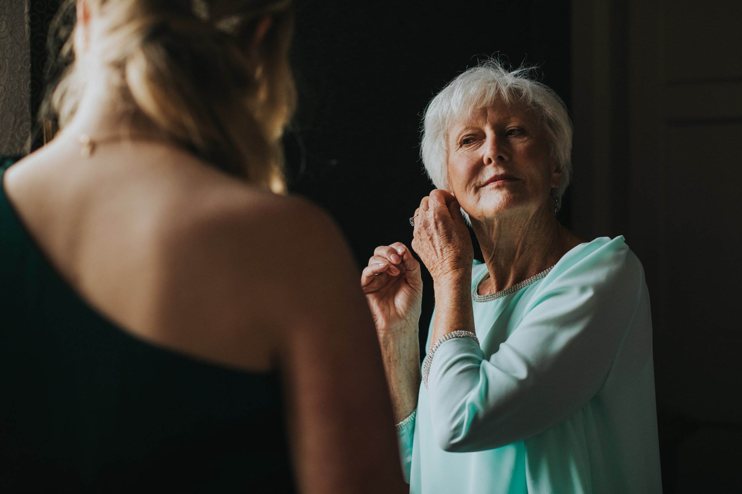 Mother of the bride puts on some earrings. 