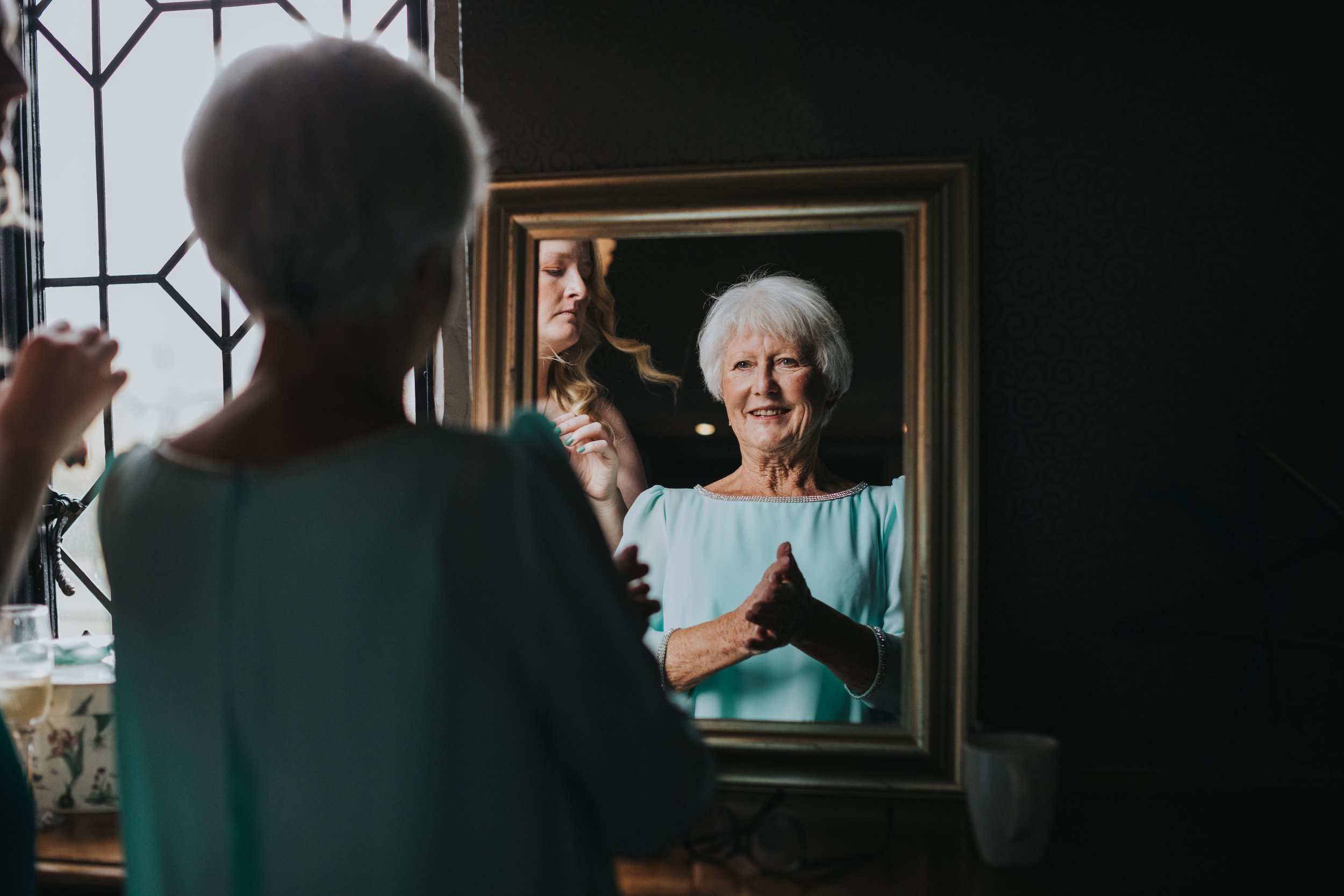 Mother of the Bride smiles as she looks in the mirror