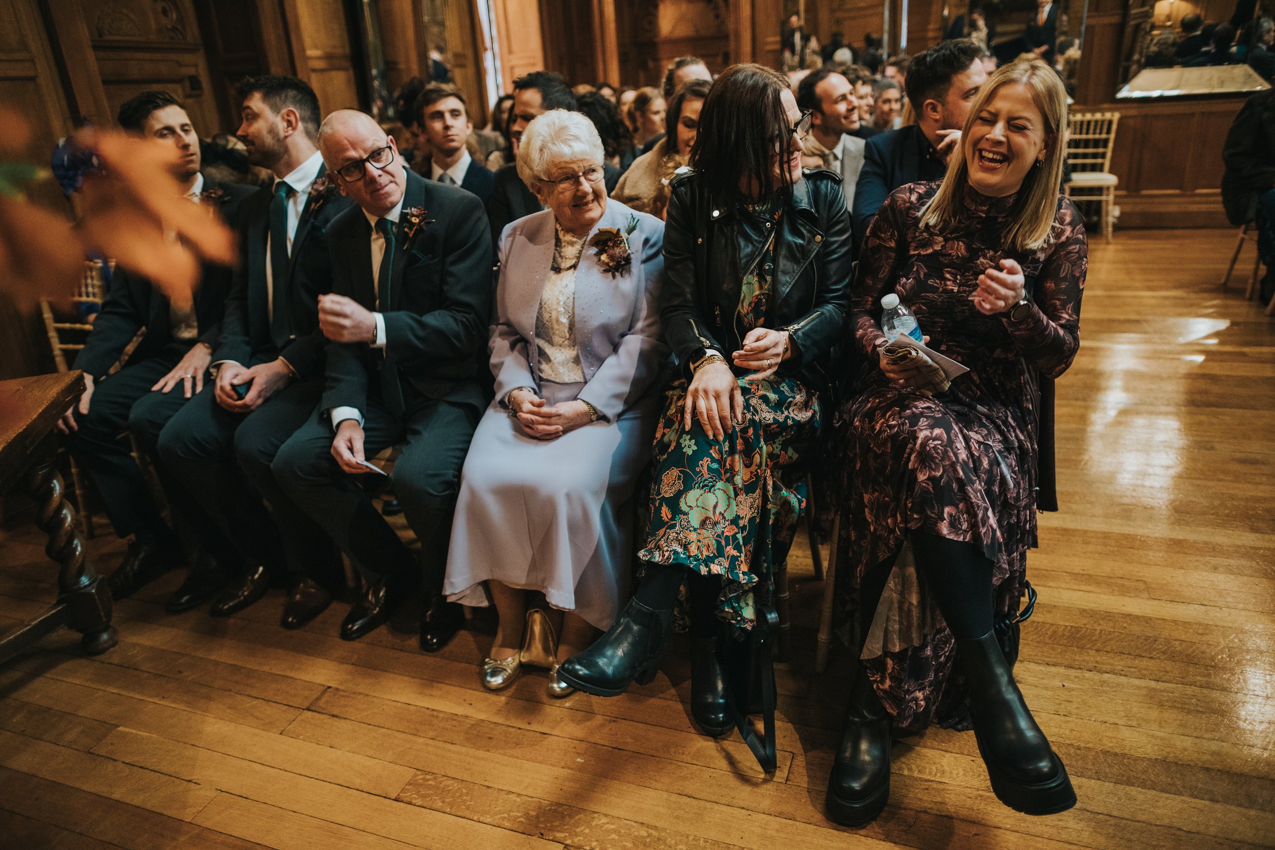 Sister of the groom laughing while sitting on the front row. 