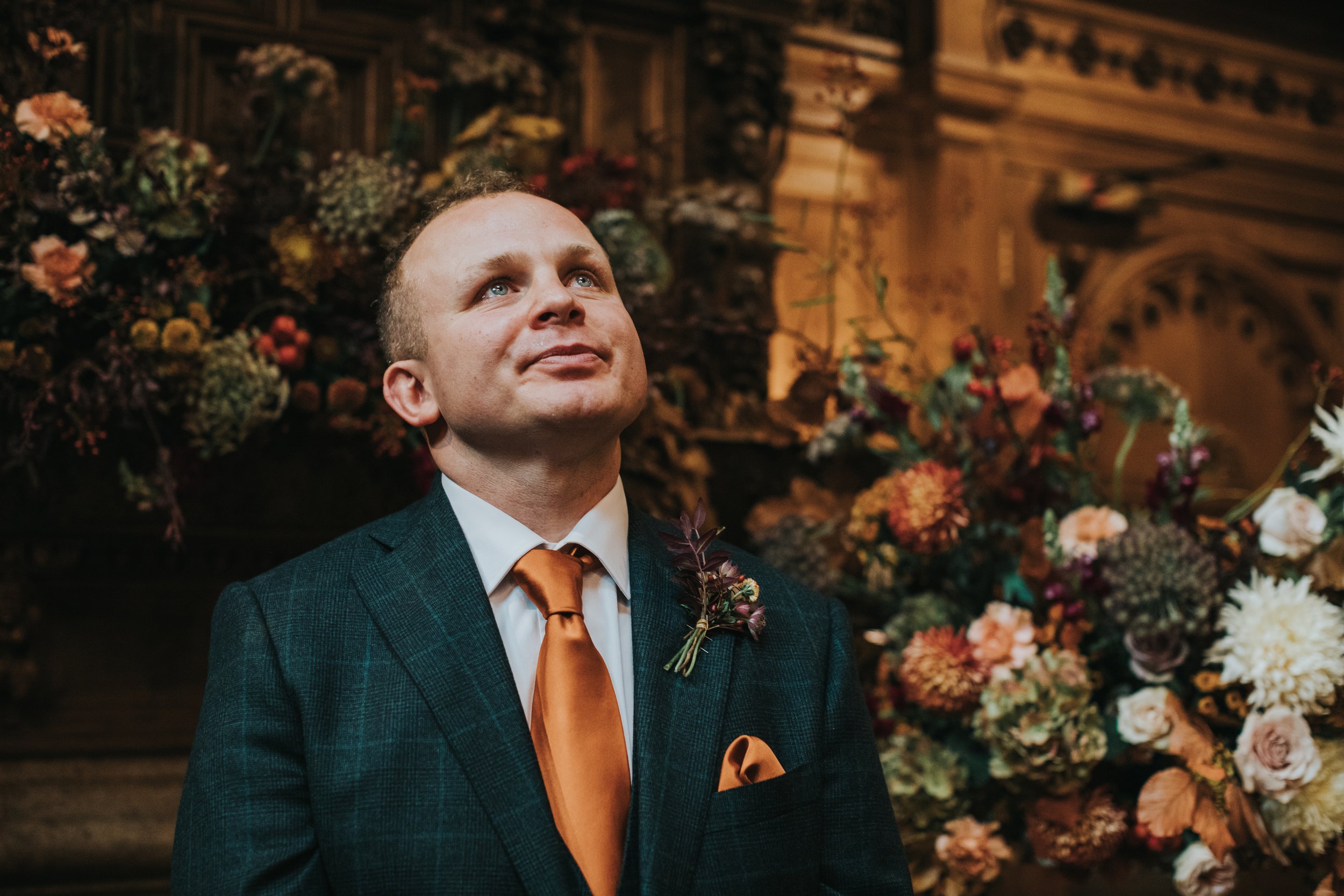 The groom looks up at his bride making her way to him with tears in his eyes. 