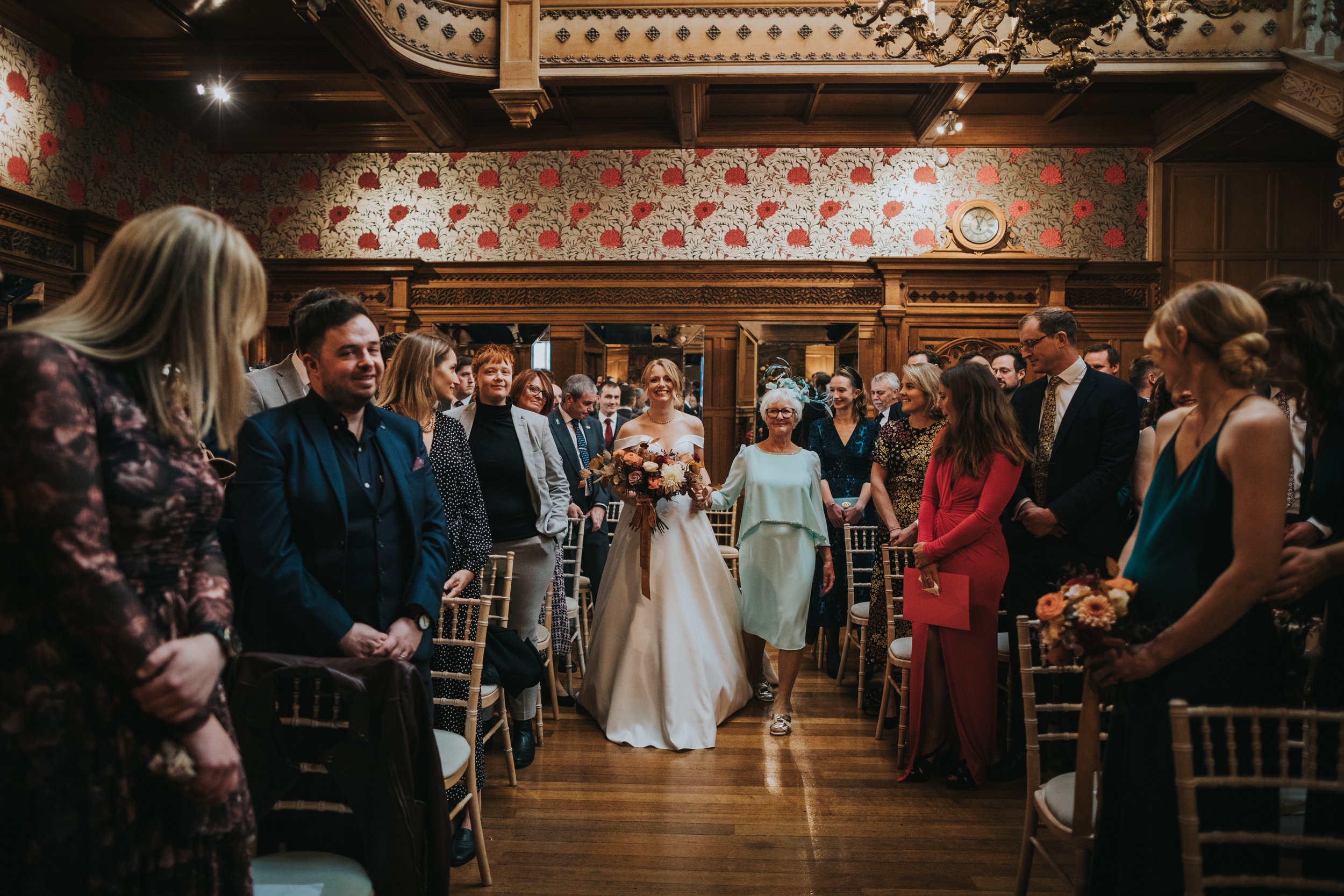 Bride is walked down the aisle by her mother. 