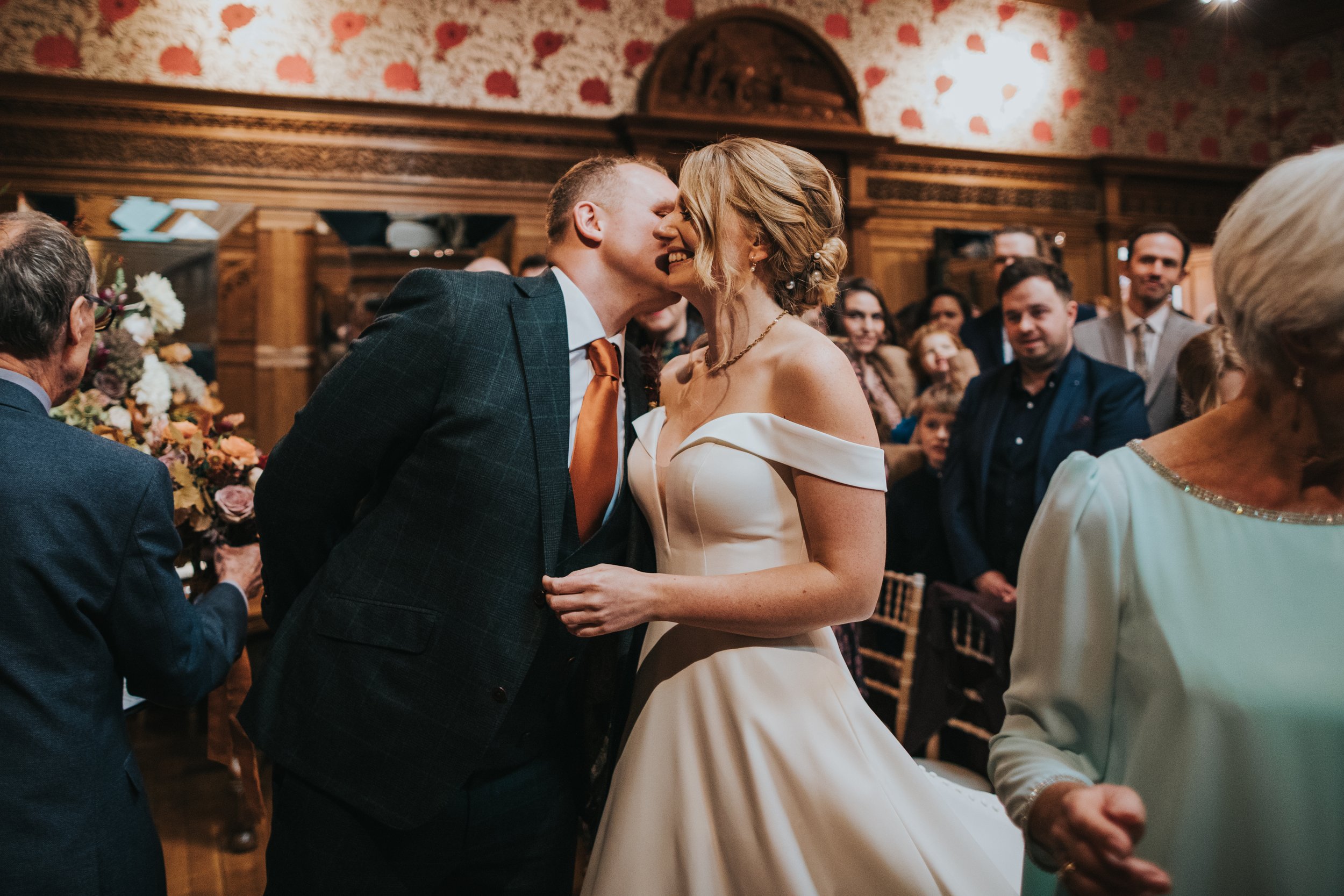 The groom greets his bride with a kiss on the cheek. 