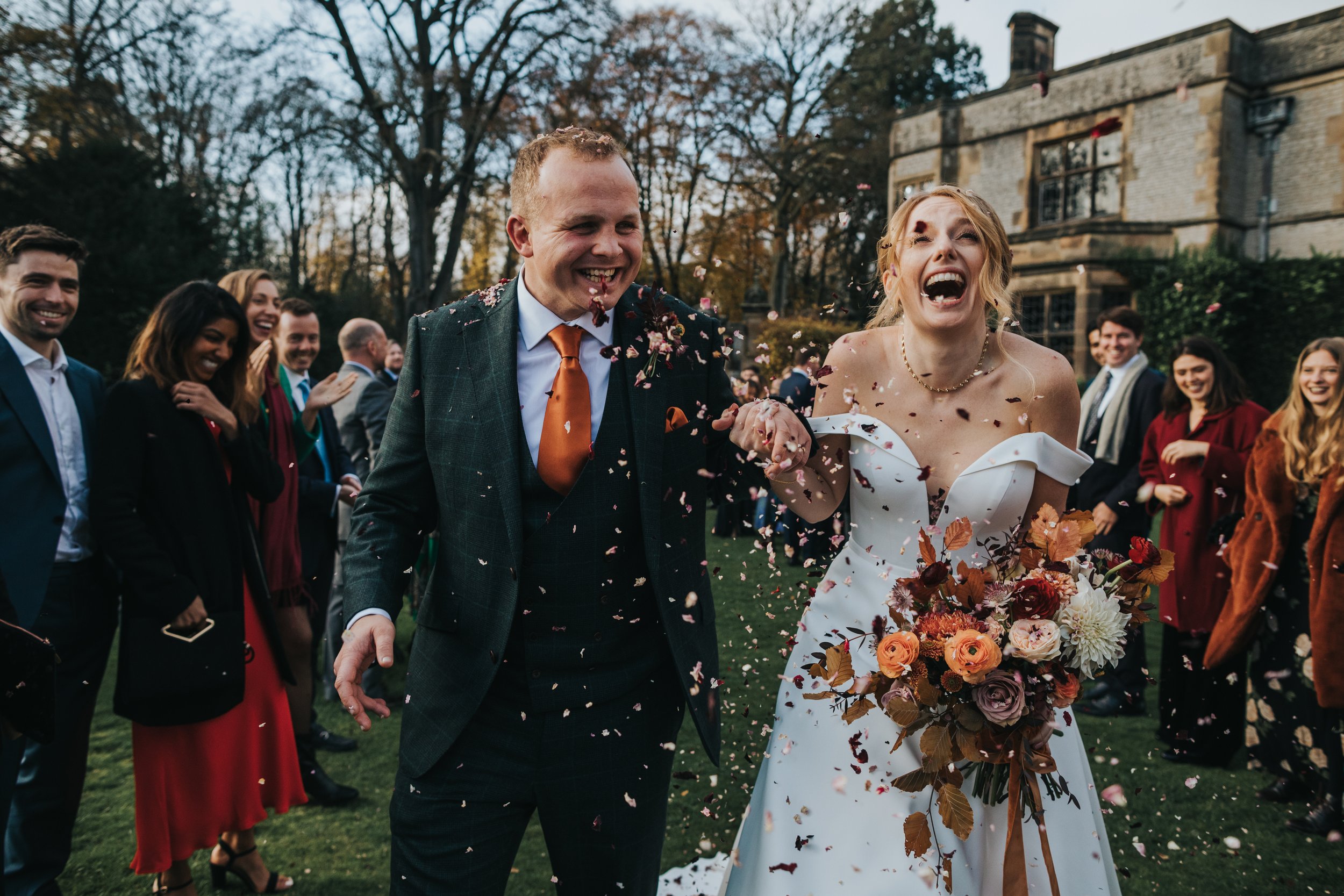 Bride laughs as they get to the end of the confetti line. 