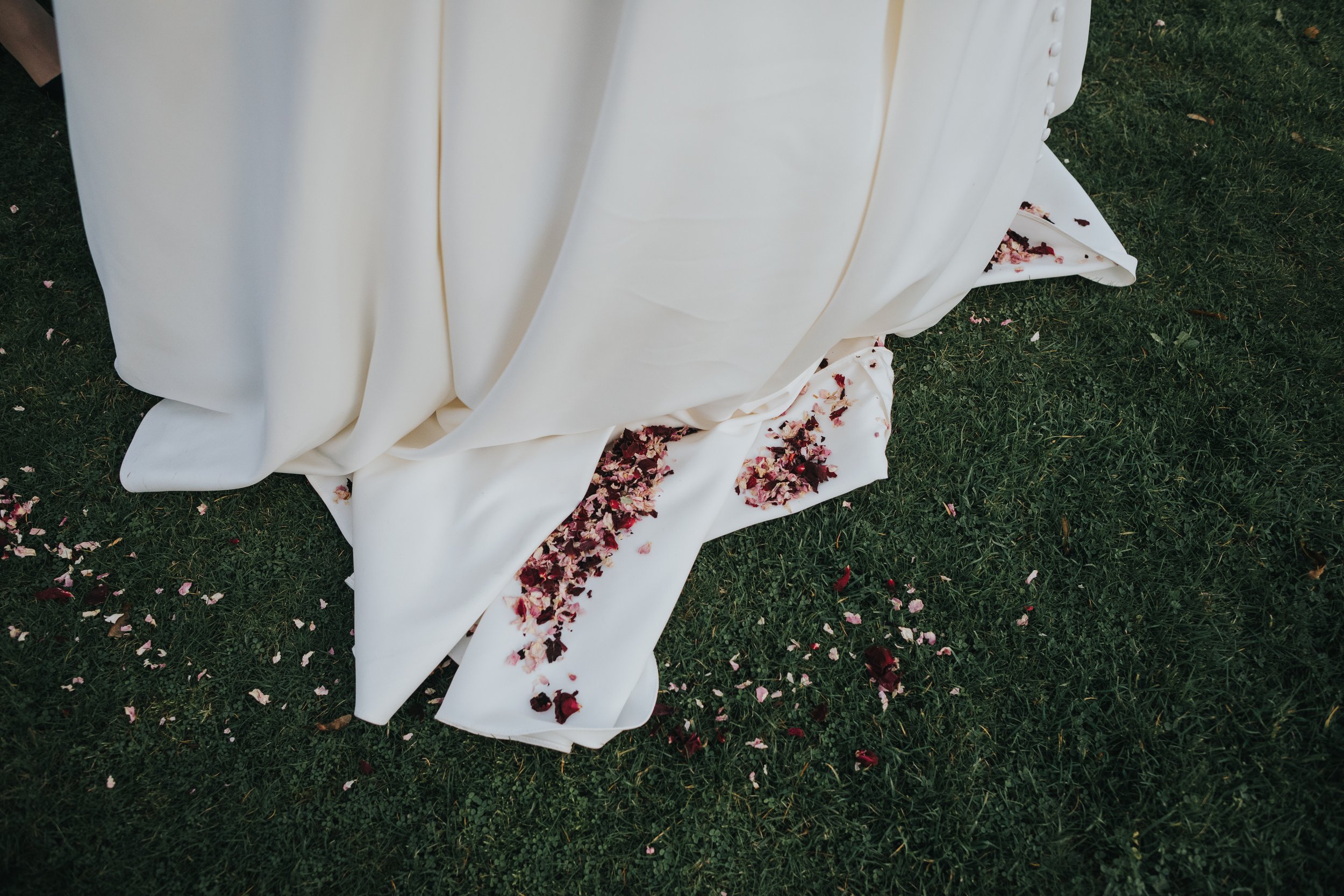 Confetti gathered in the folds of the brides white dress. 