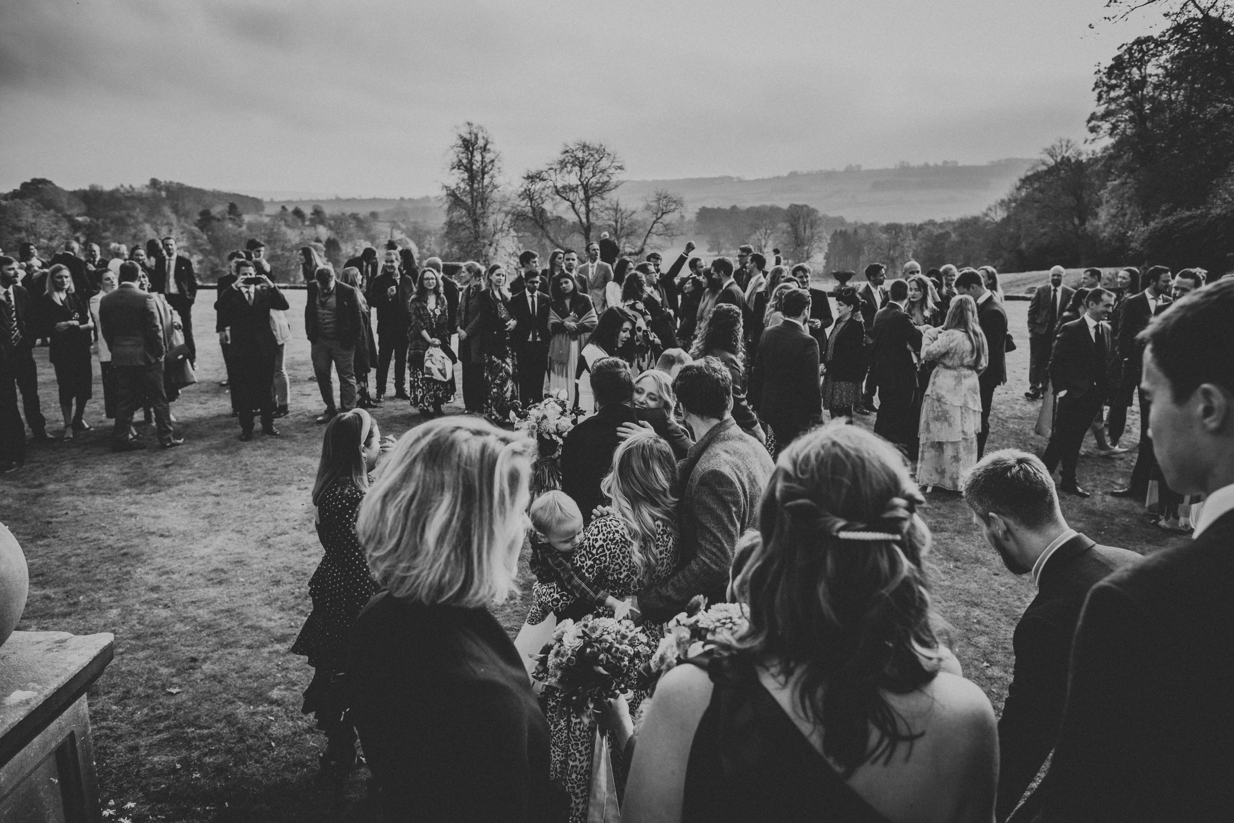 Black and white photo of Bride and Groom receiving guests in the gardens of Thronbridge Hall. 