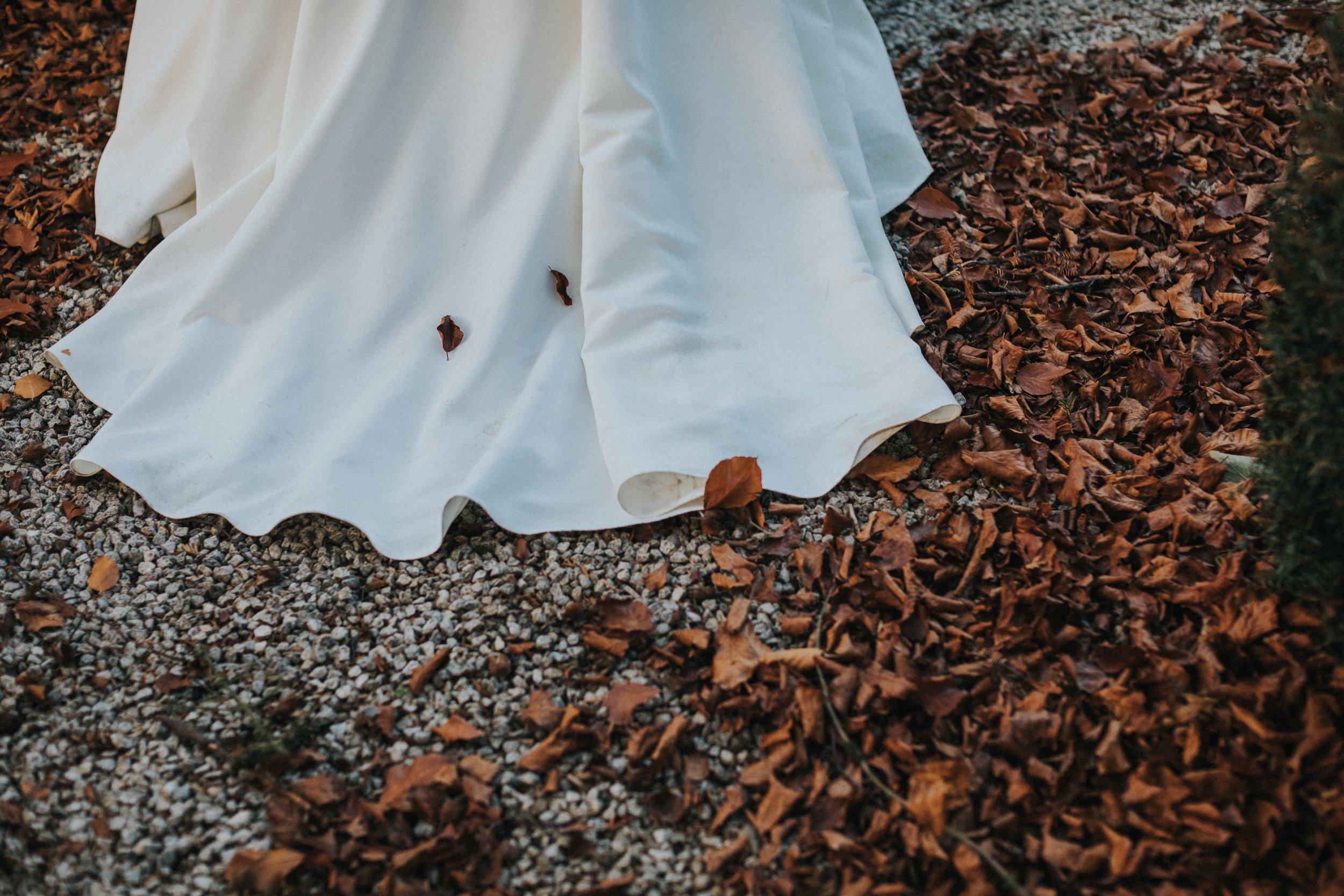 Tail of wedding dress amongst the autumn leaves. 