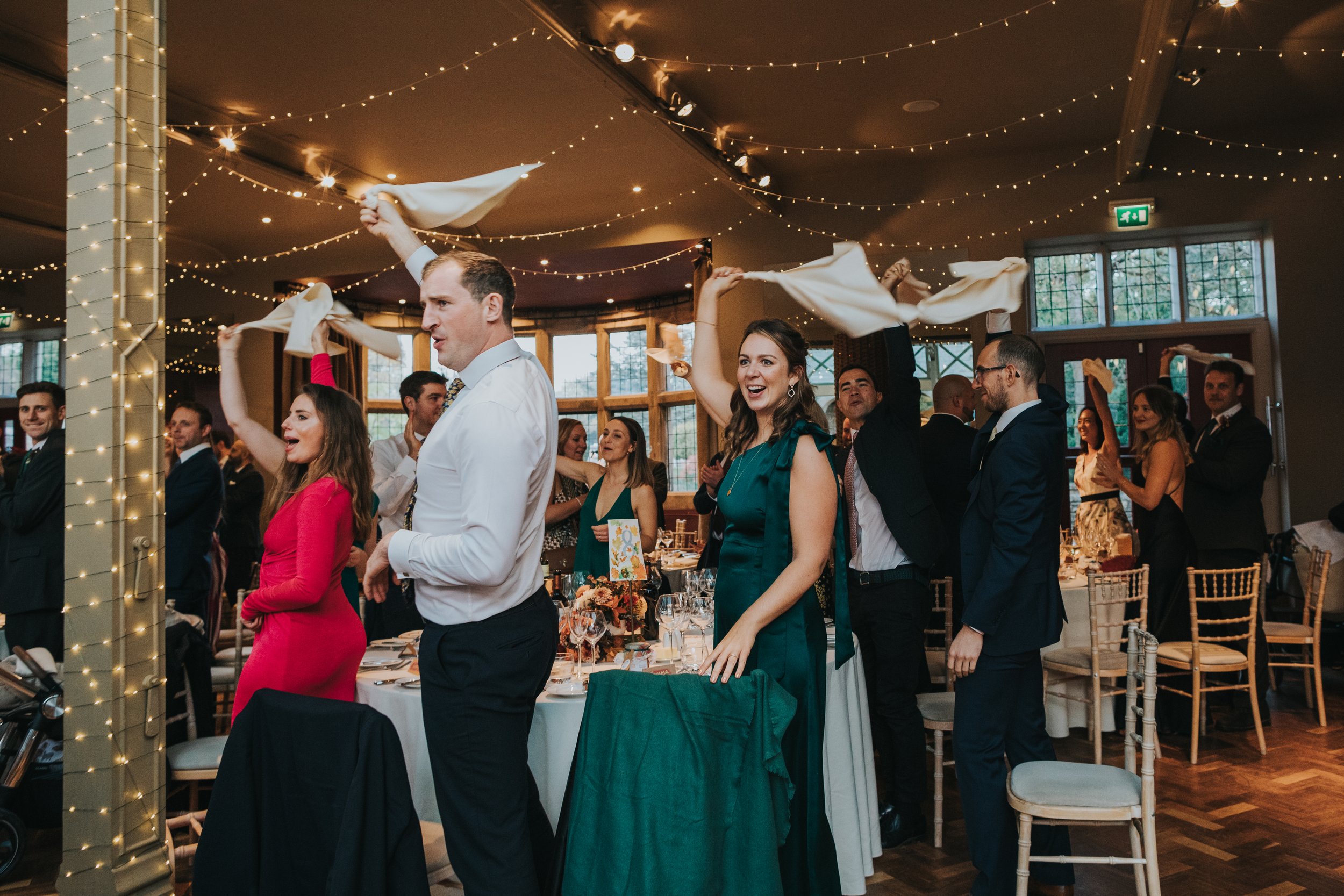 Wedding guests stand and swirl napkins in the air on couples arrival.