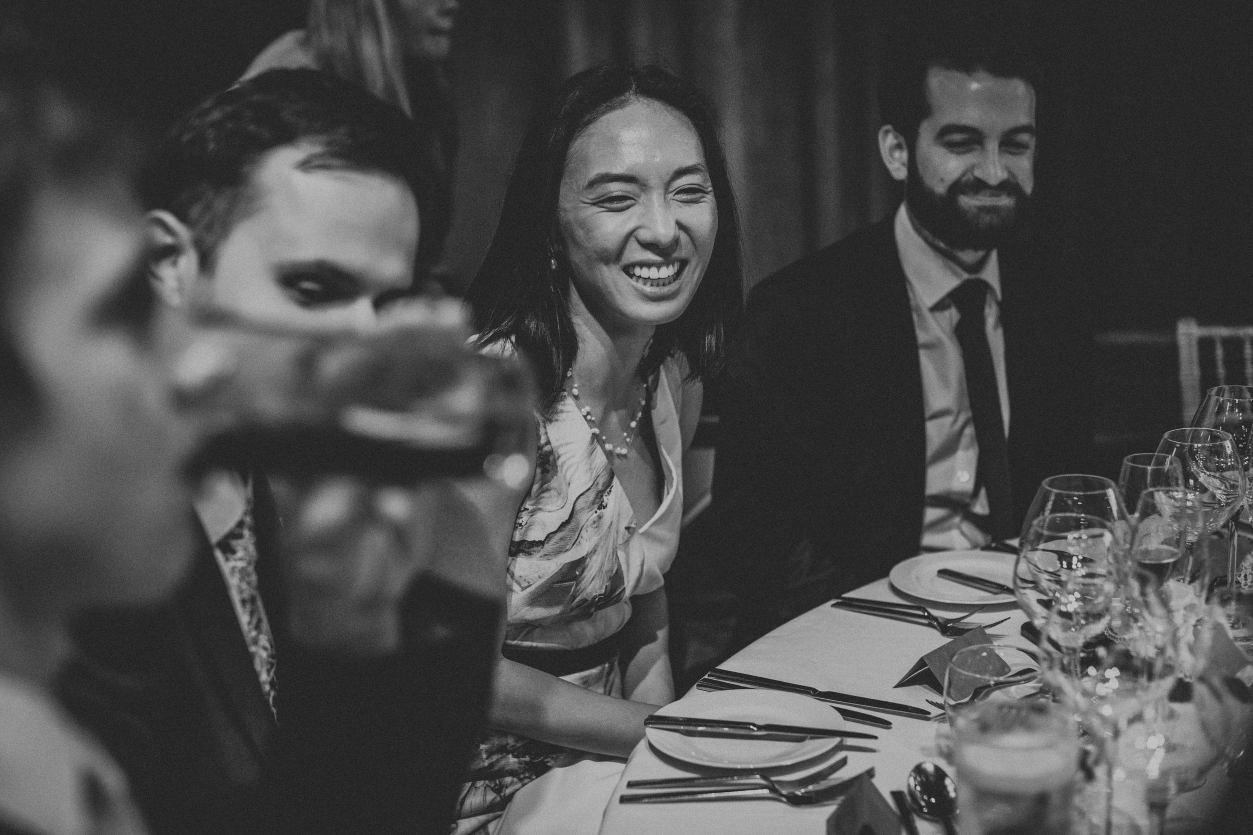 Black and white photograph of wedding guest smiling. 