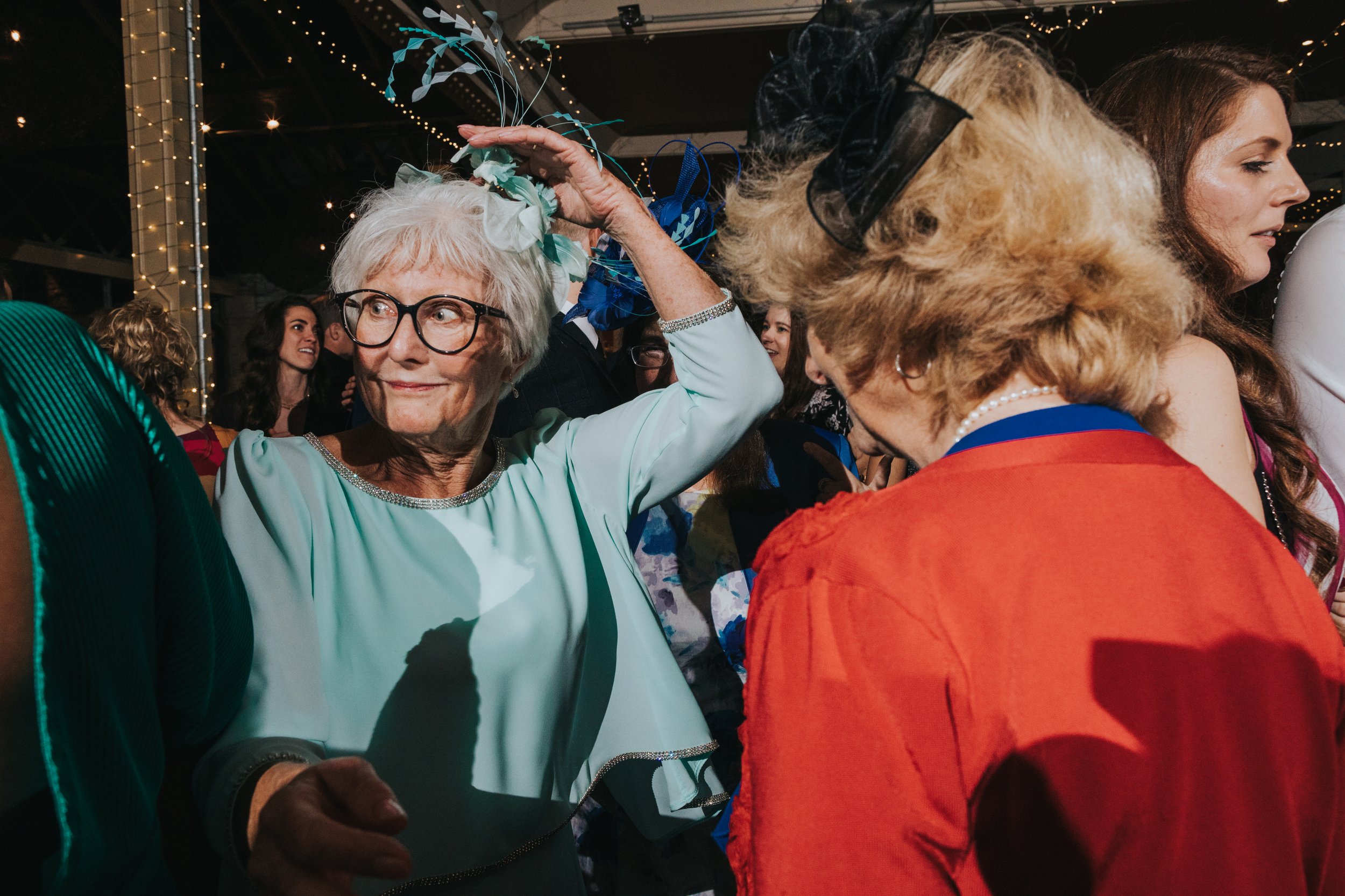 Mother of the bride holds onto her hat while dancing. 