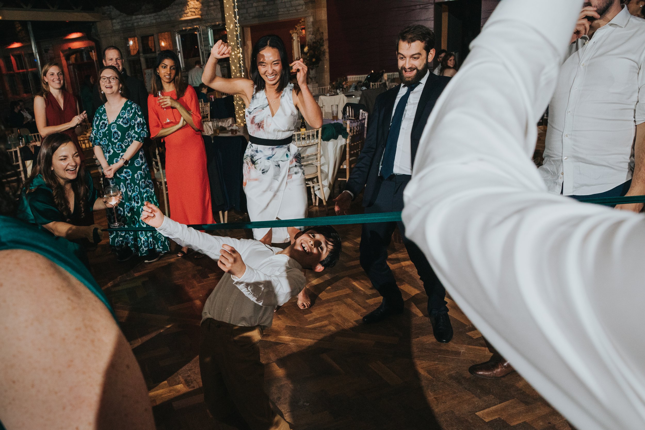 Child smiles while doing the limbo on dance floor. 