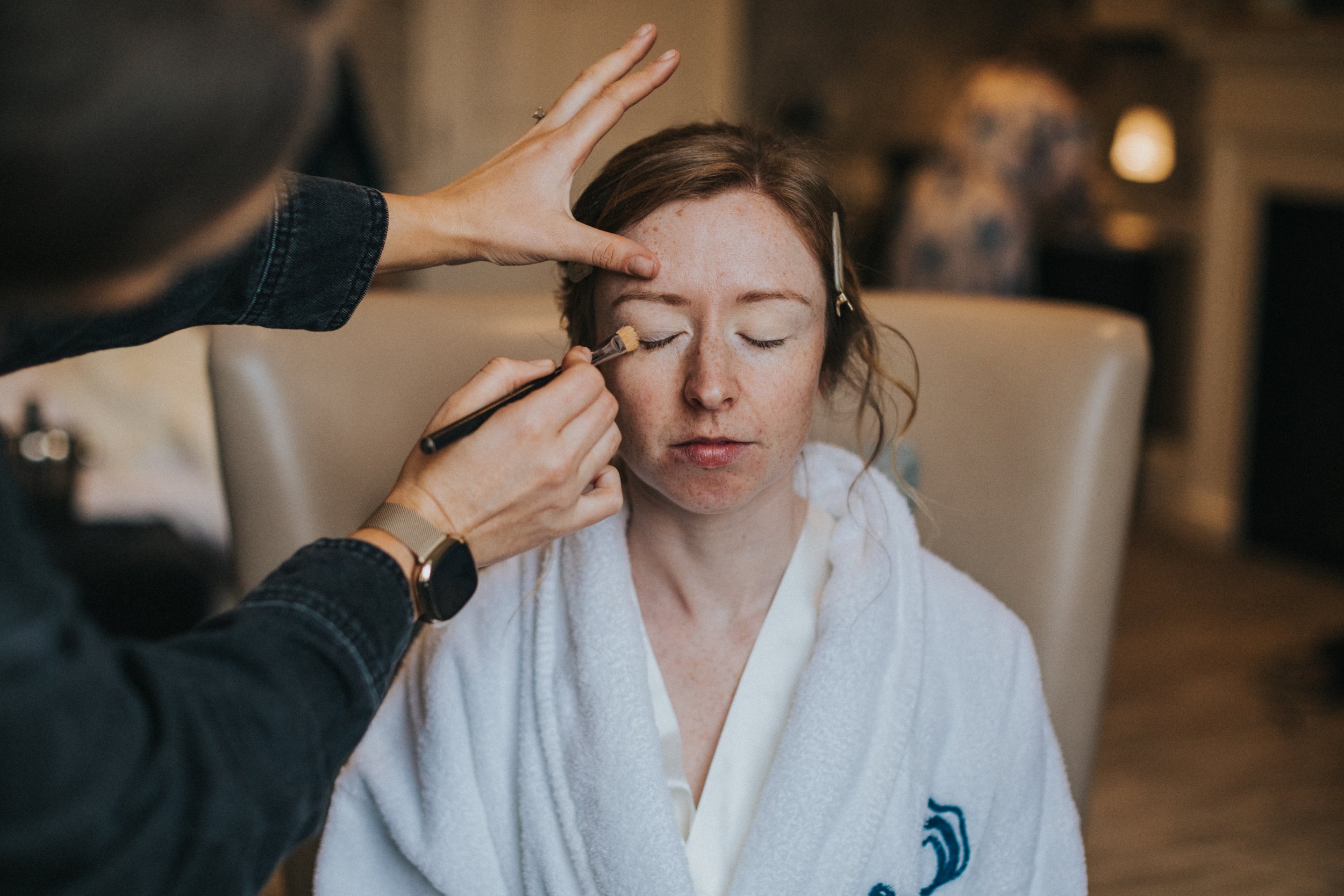 Bride has her eye make up put on. 