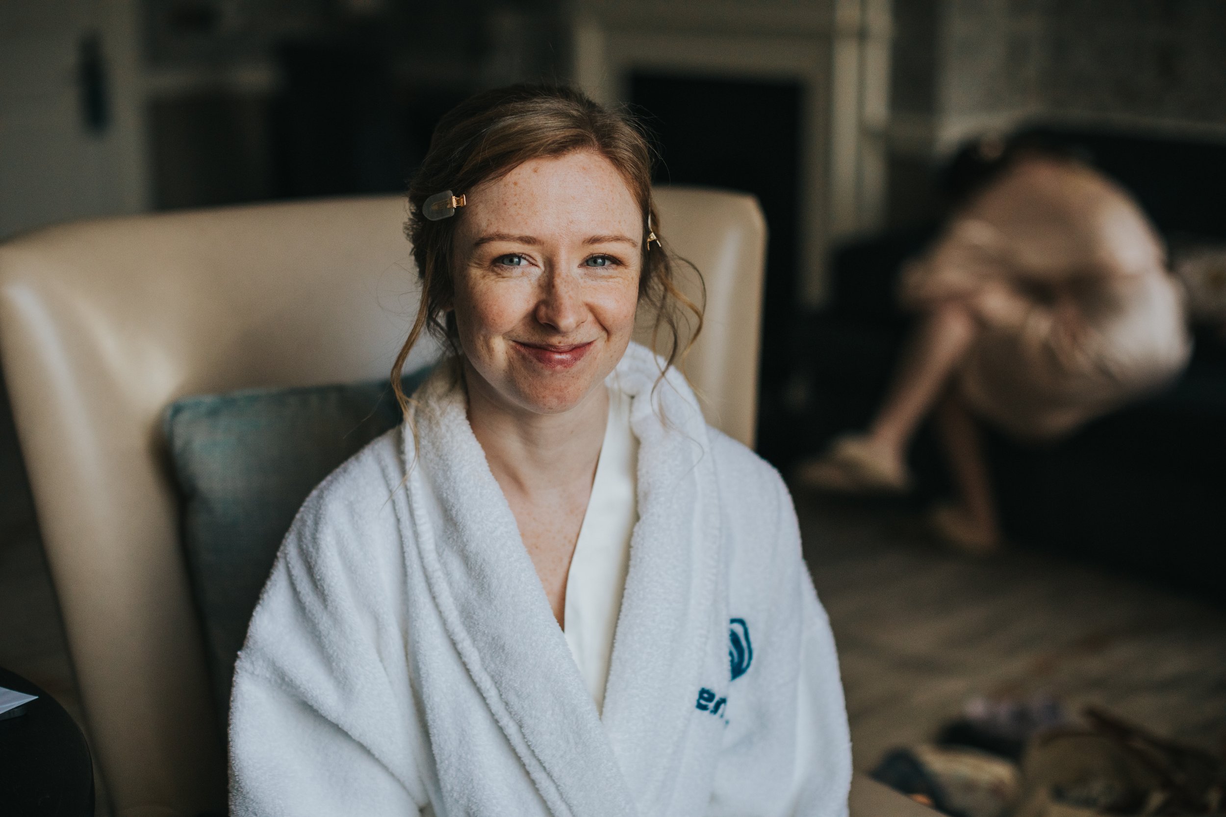 Bride looking to the camera and smiling in her hotel dressing gown. 