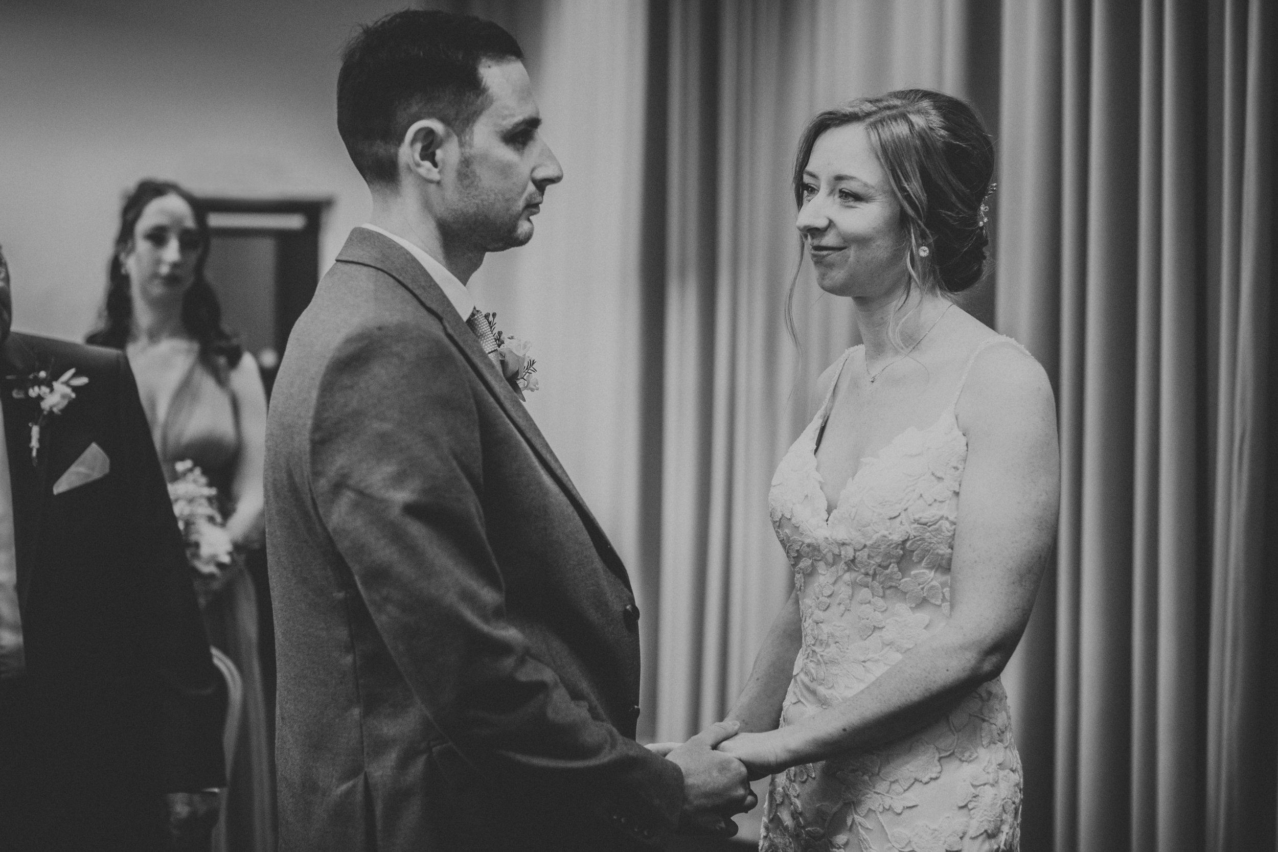 Black and white photo of bride and groom standing looking into each others eyes. 