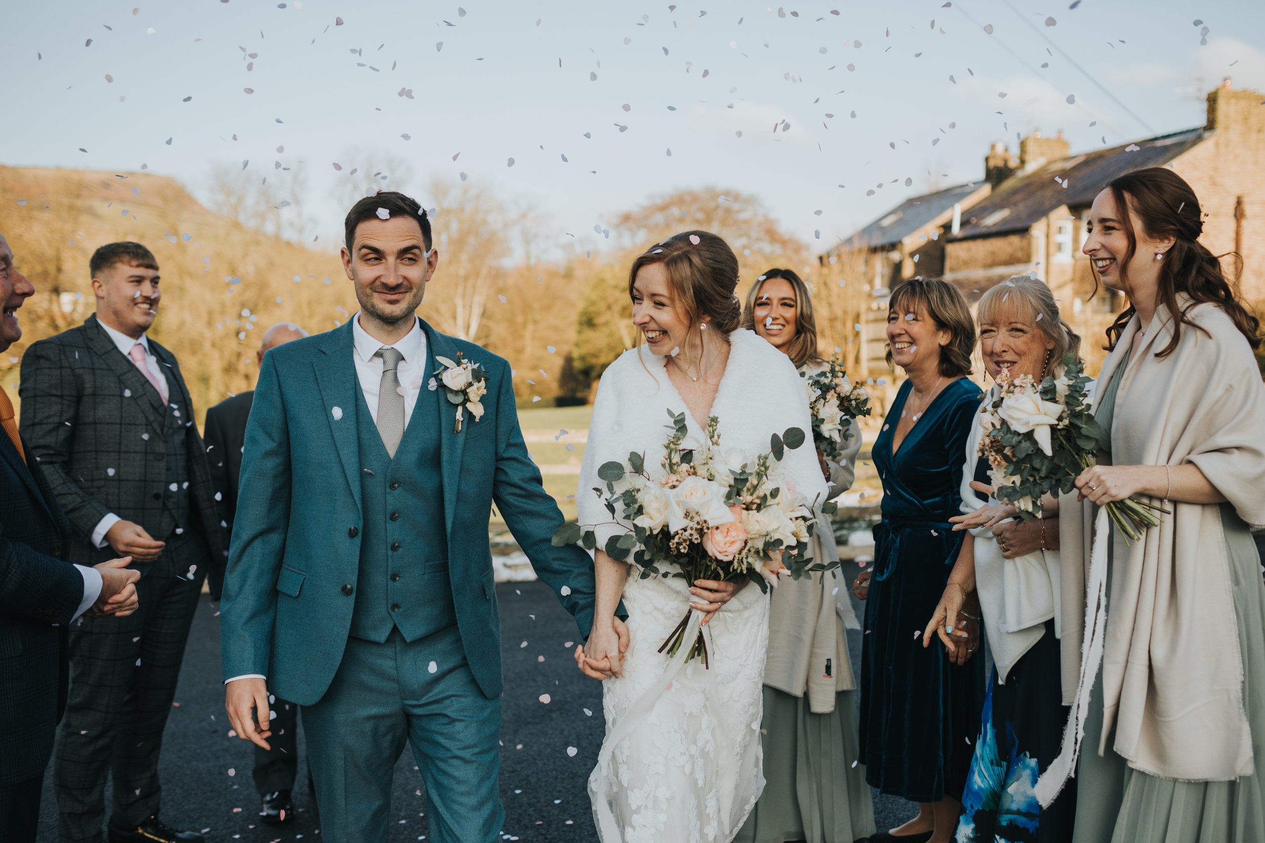 Groom gives bride a Mr Bean side eye as they have confetti thrown at them. 